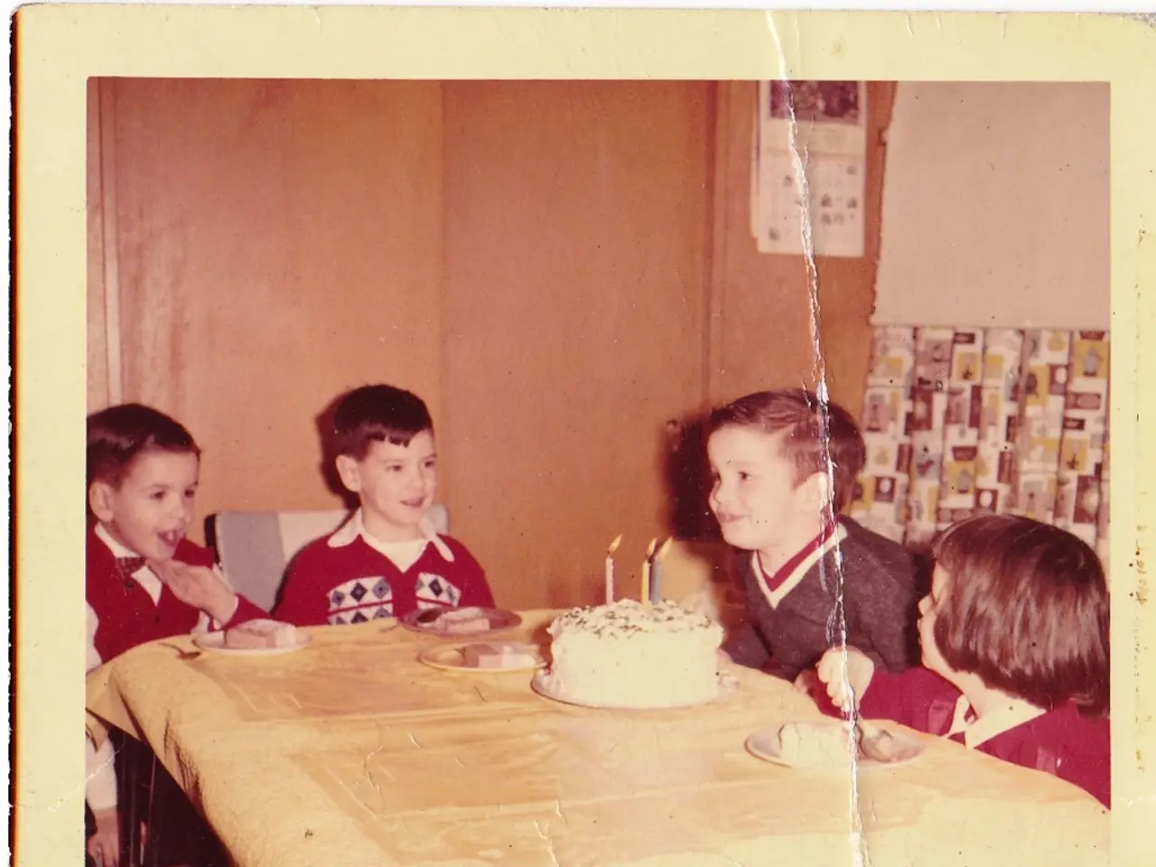 In this image I see a photo over here and I see 4 children and I see a table on which there is a...