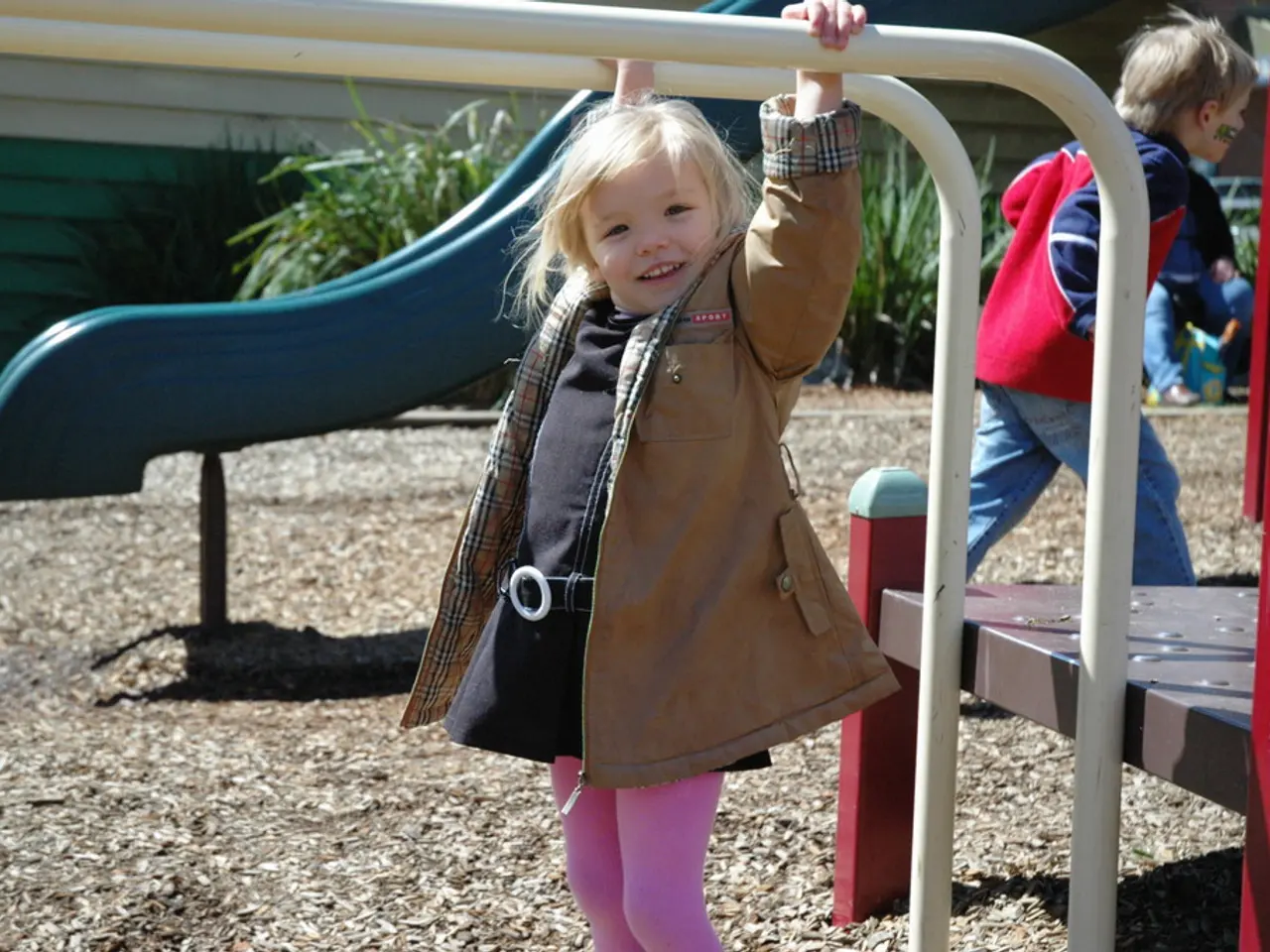 In this picture there is a kid wearing jacket is standing and holding iron poles above her and...