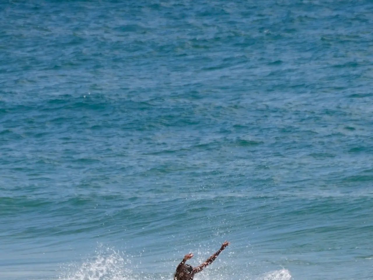 In the image there is water. Also there is a man standing on the surfboard and surfing on a wave.