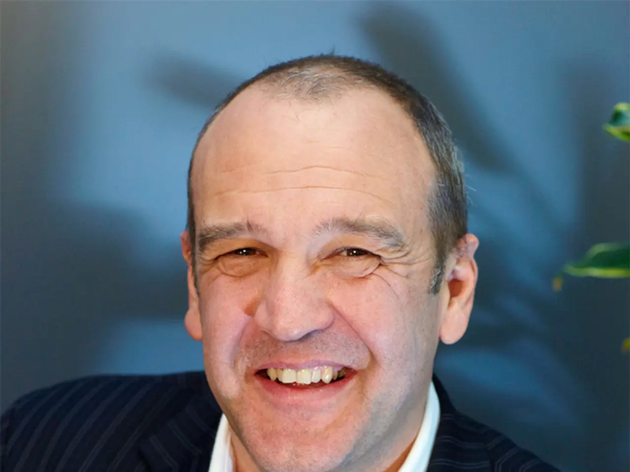 This picture shows a man with a smile on his face and he wore a black coat and a white shirt.