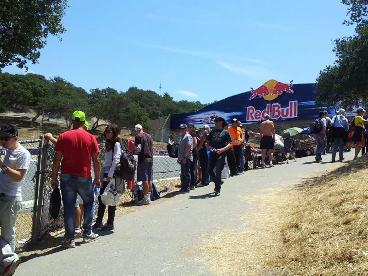 In the image we can see there are people standing near the fencing, there is a banner kept on the...
