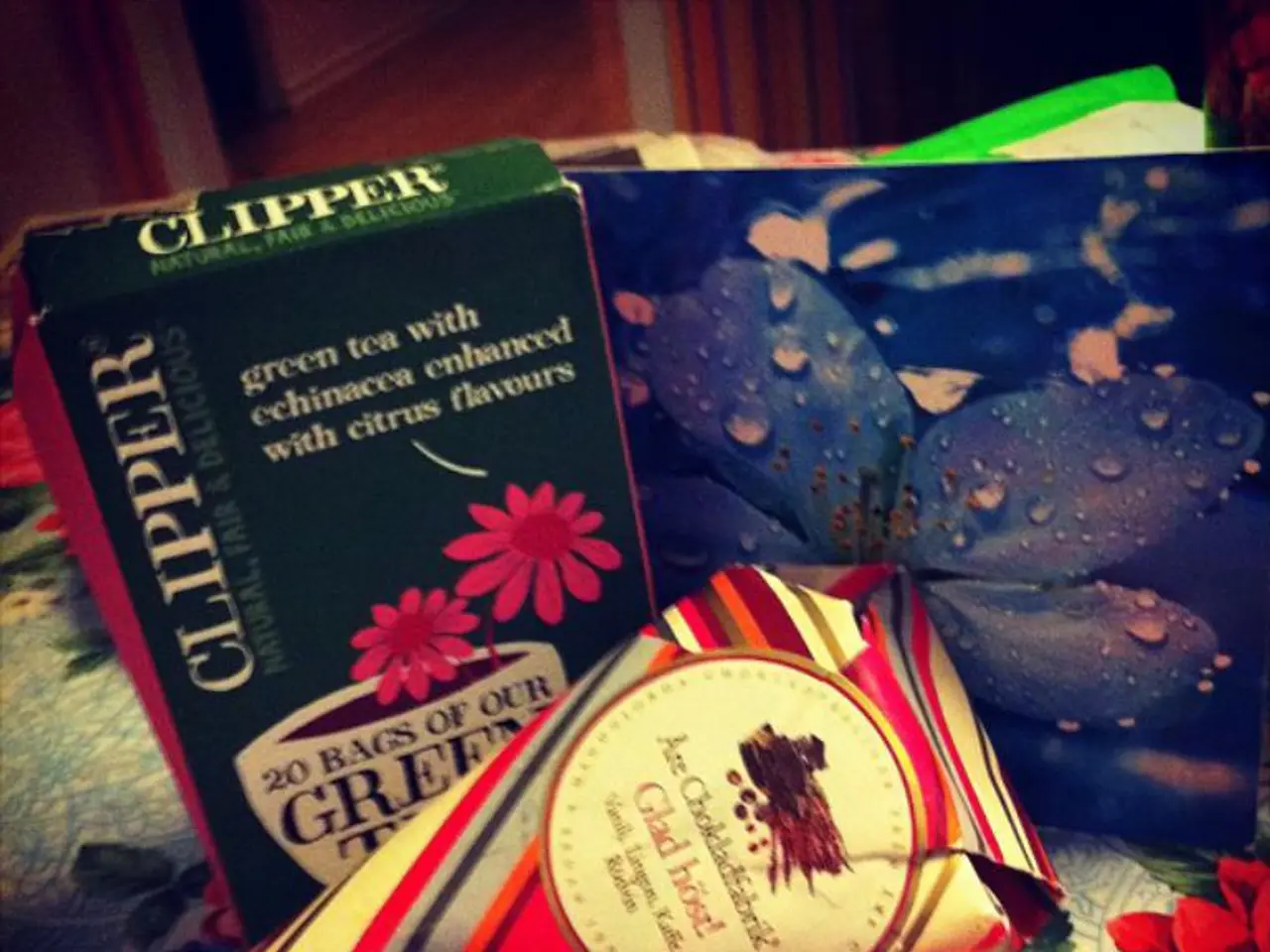 In this image we can a carton, a card, and a paper placed on the cloth. In the background there is...