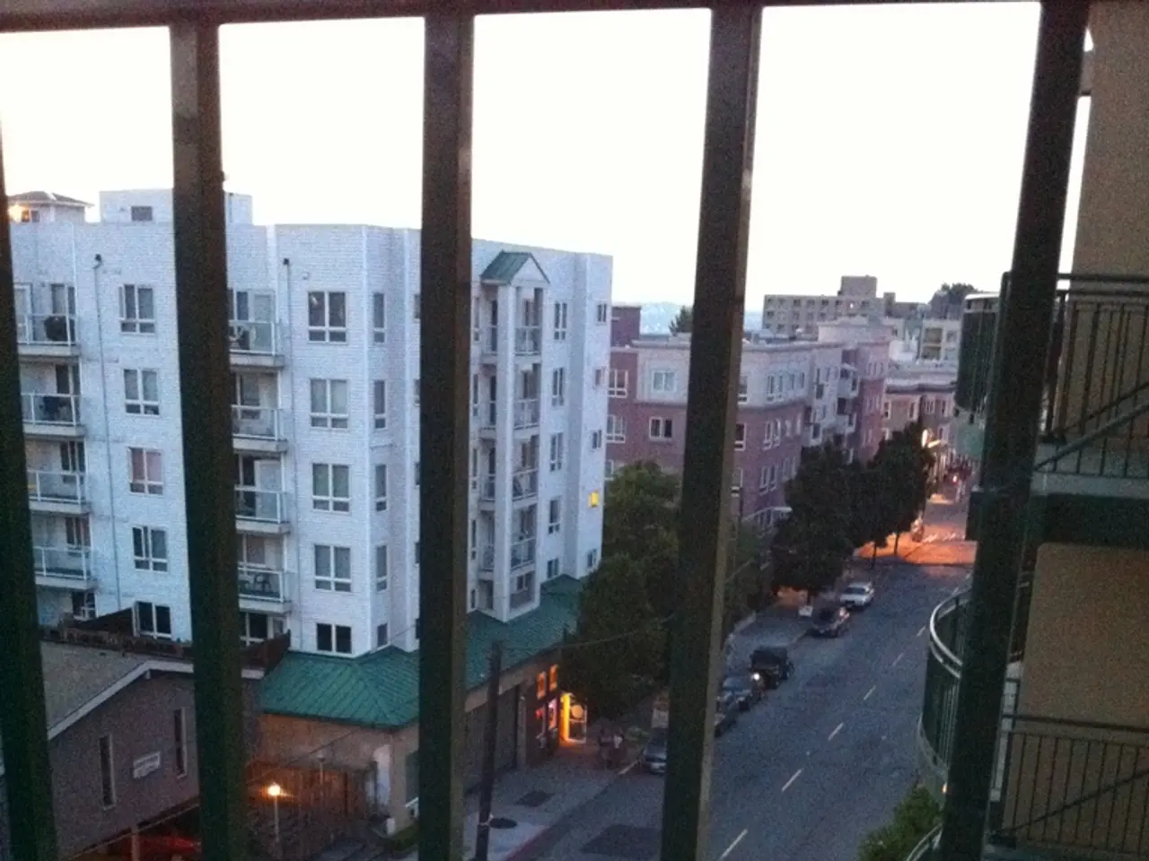 In this image we can see a grille, behind the grille so many buildings are present and cars are...