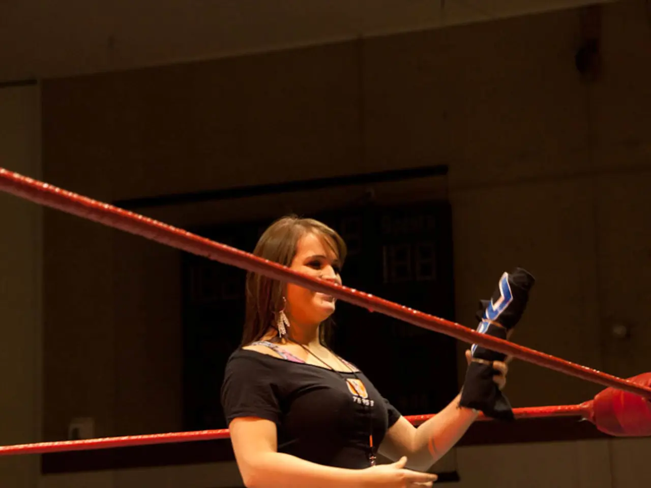 In this picture we can see a woman in a boxing ring and holding a cloth with her hand and smiling...