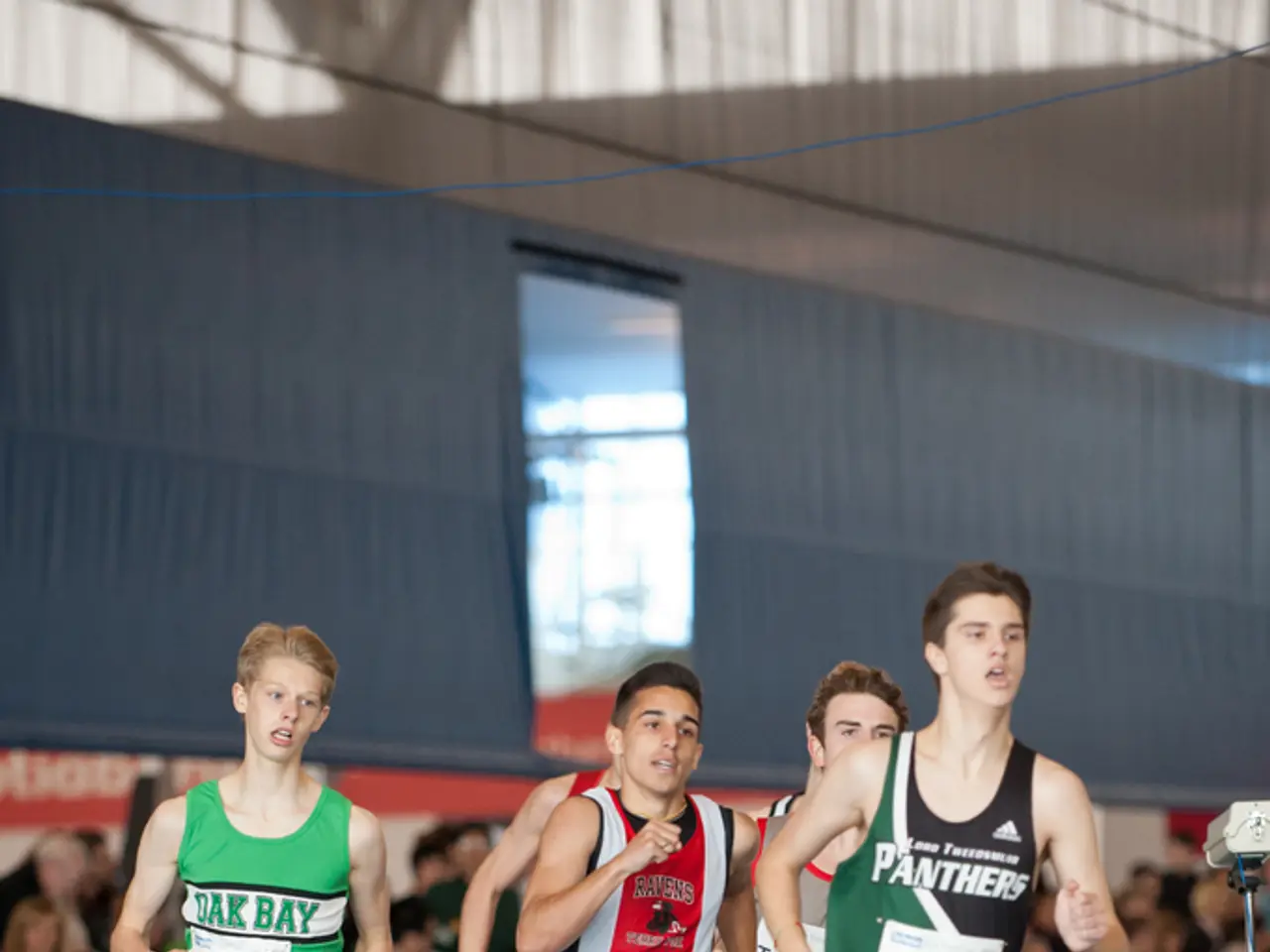 In the picture there is an indoor stadium, there are some people running, beside there are many...