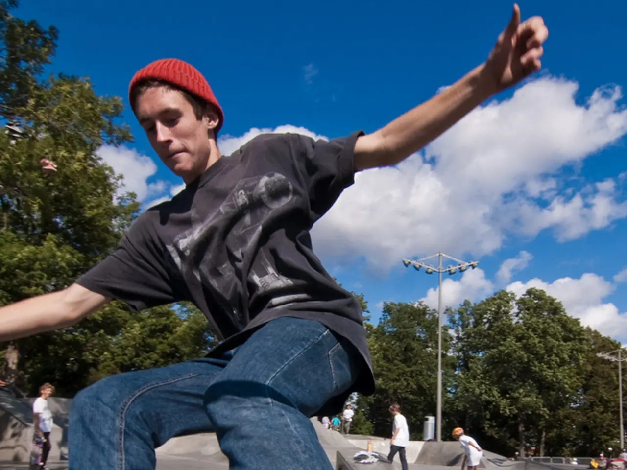 This image is clicked outside. There are trees in the middle. There are so many persons skating in...