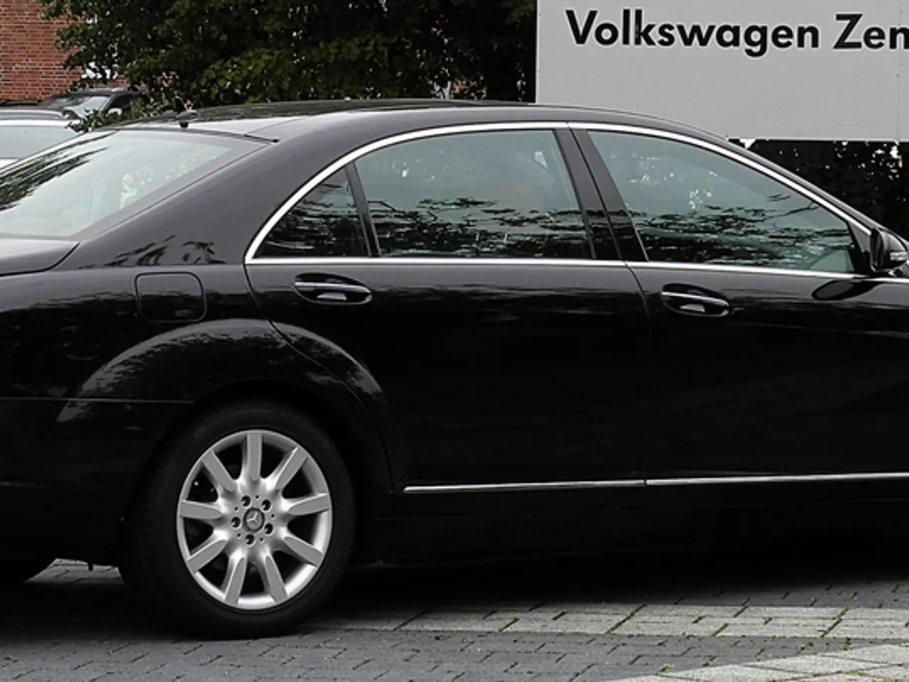 In this image we can see some cars parked near the wall, one pipe attached to the wall, some trees,...