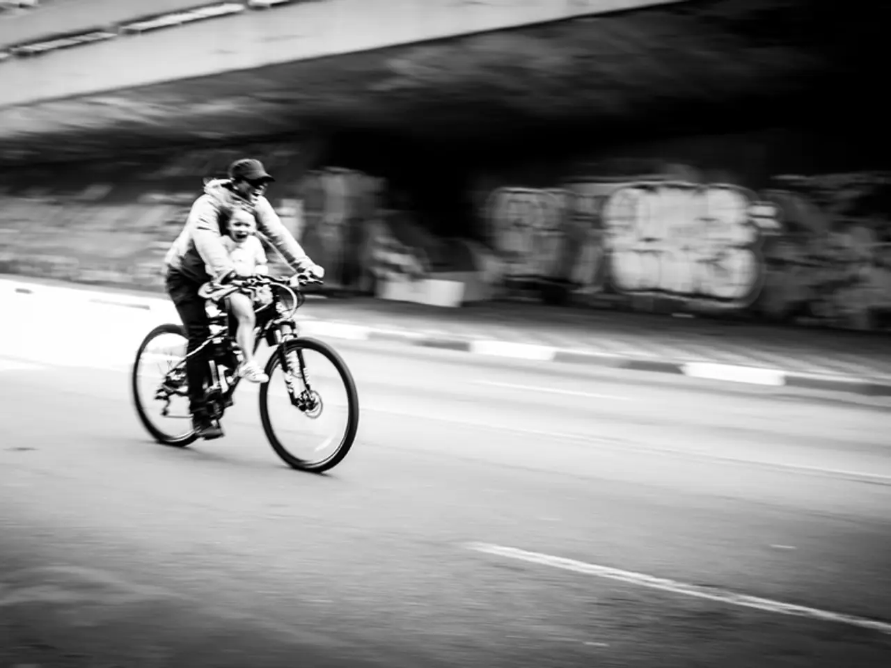 This is a blurred picture of a man and a girl riding the bicycle on the road.