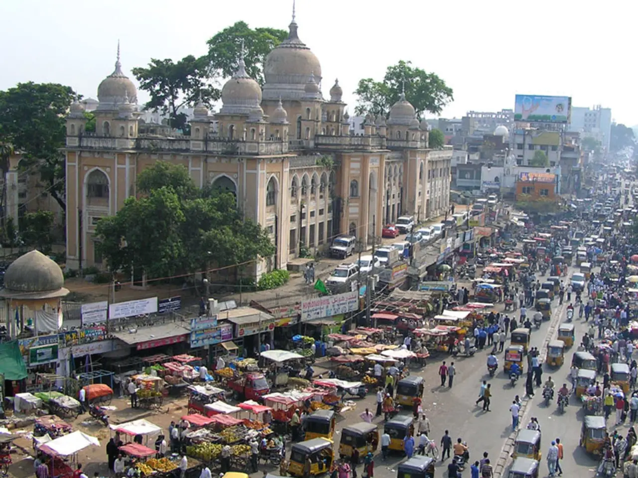 In this image there is a road on which there are so many people and so many vehicles. Beside the...