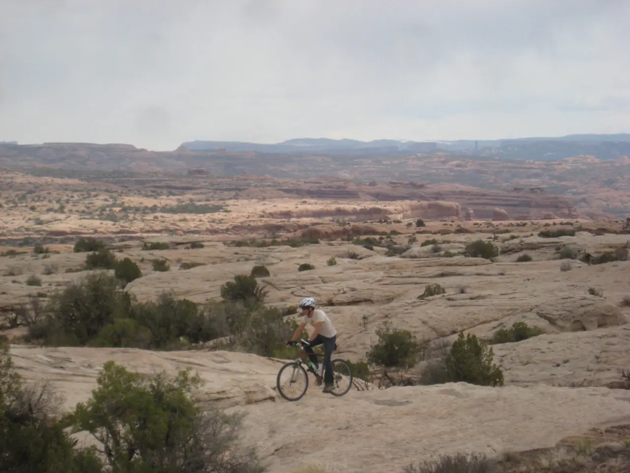 In the center of the image there is a person riding a bicycle wearing a helmet. At the bottom of...
