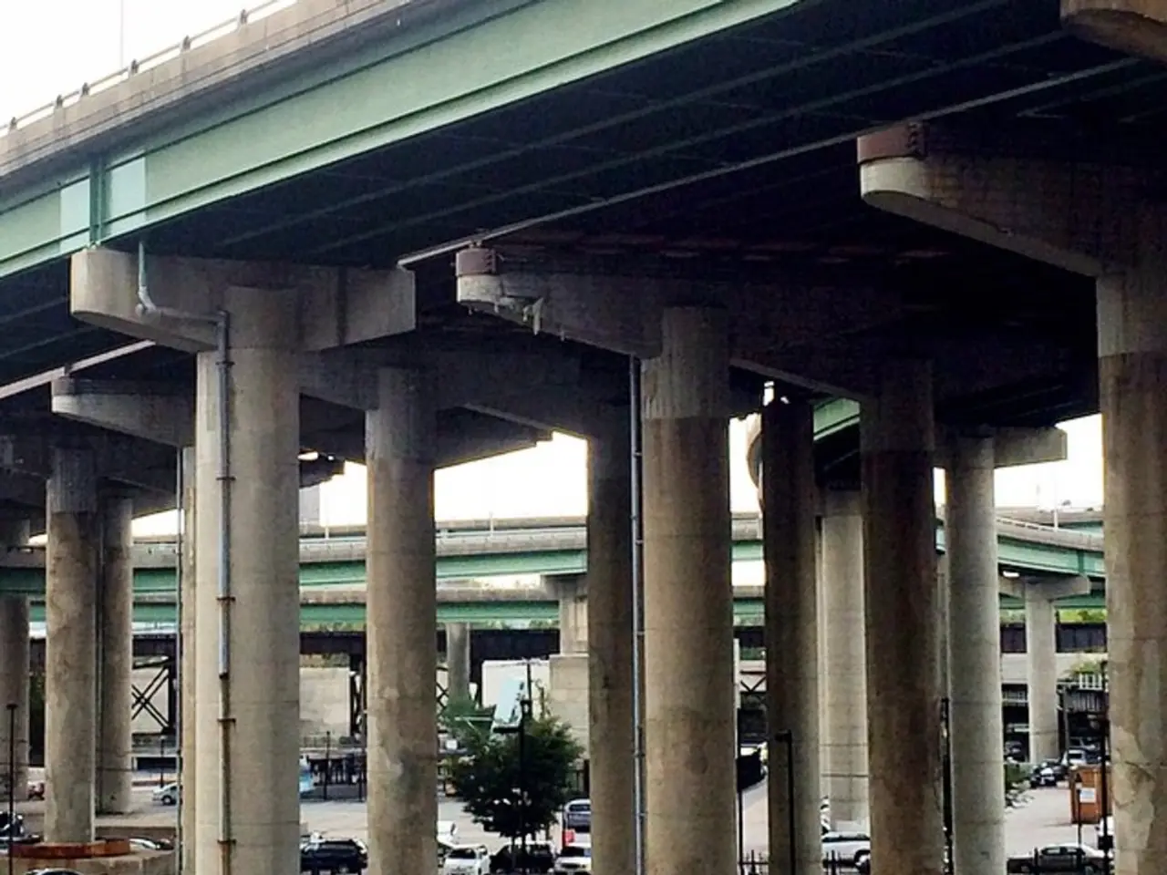 In this image we can see flyovers which are in green color and road. So many cars are parked on the...