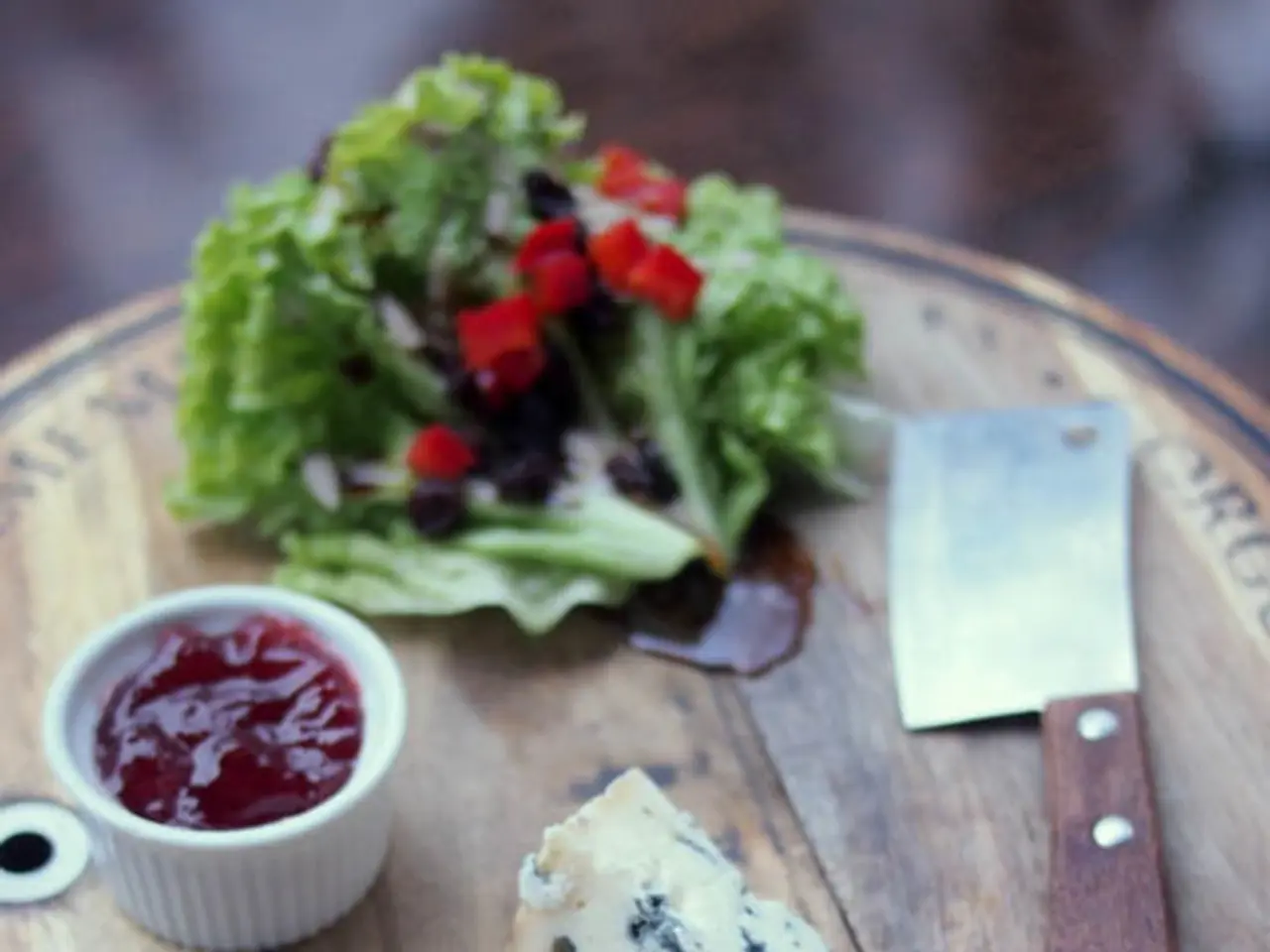 In this picture we can see a wooden chopping board, we can see leafy vegetable, a cup, a knife and...