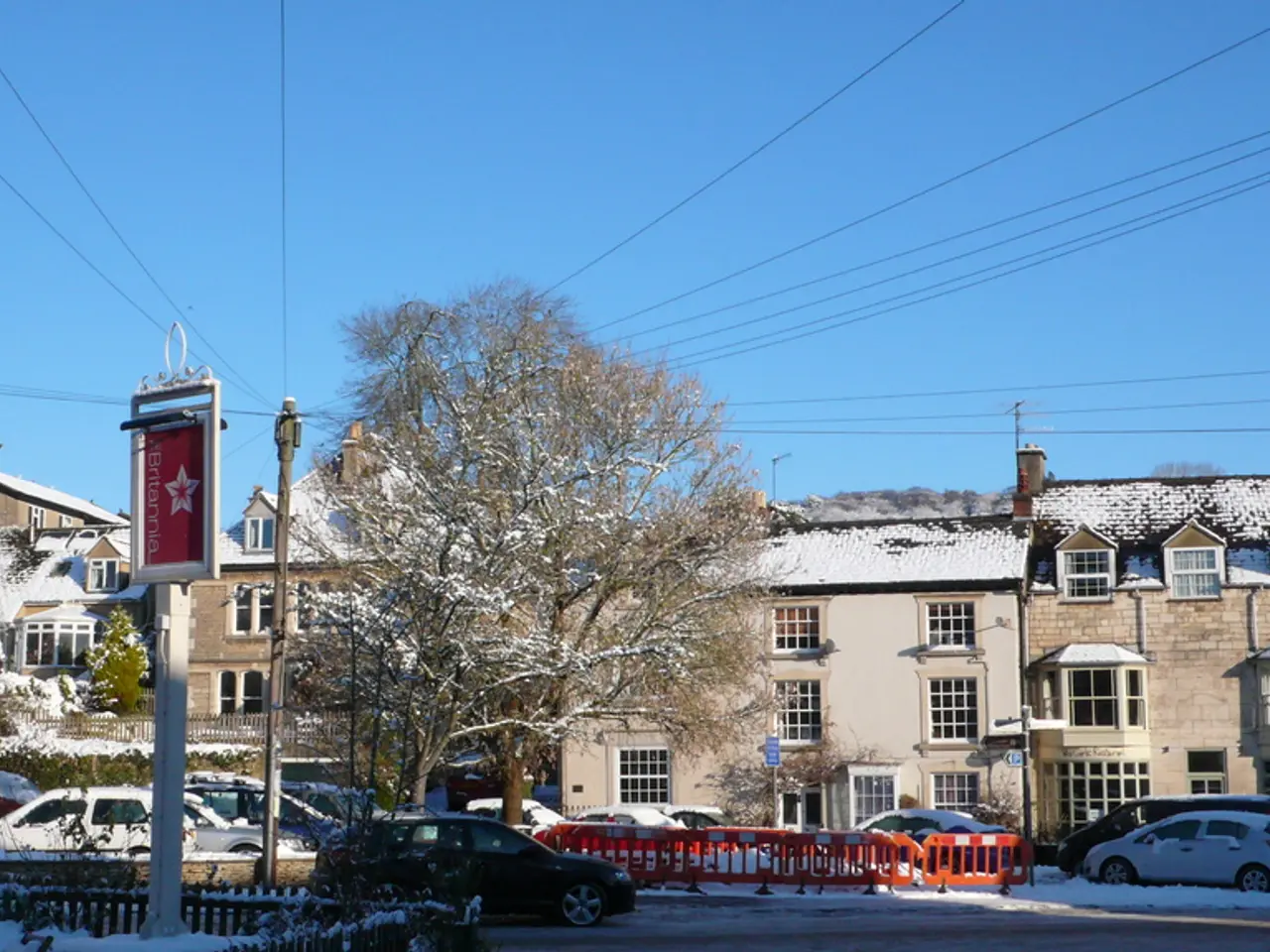 In this picture we see vehicles on the road covered with snow. In the background we have many...