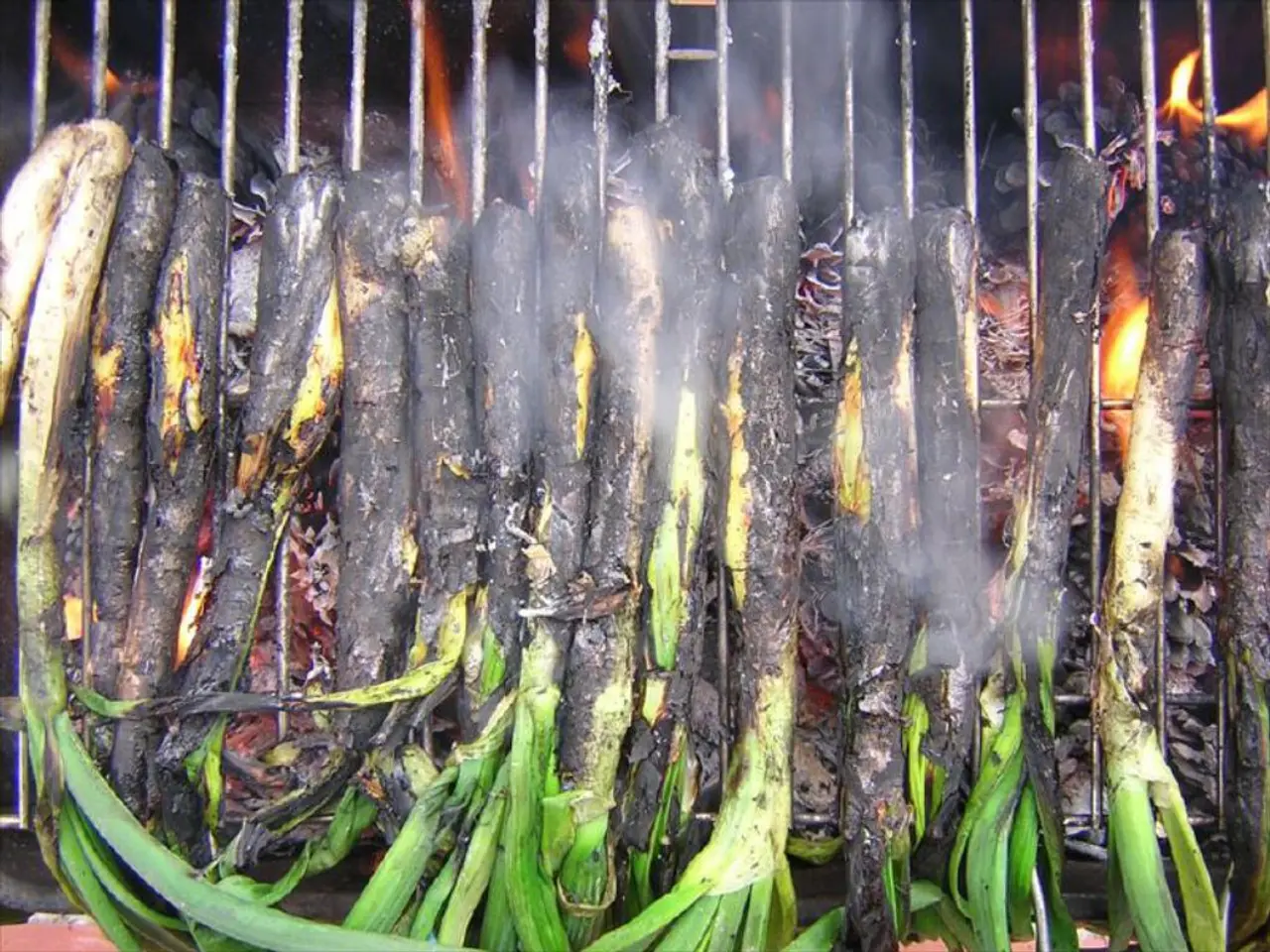 In this picture we can see leafy vegetables on the grills and we can see fire.
