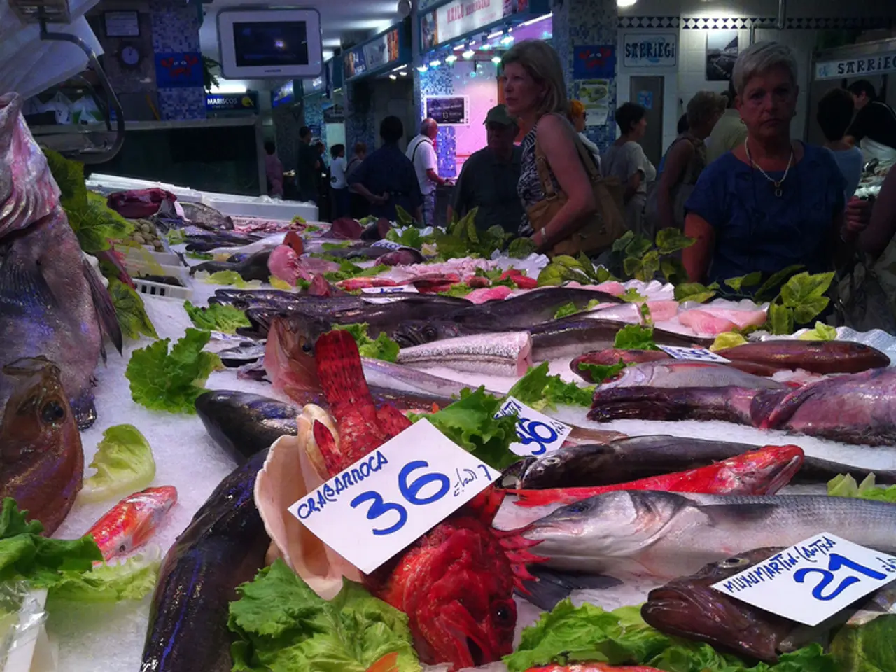 In this image we can see that there are so many fishes of different varieties are kept on the ice....