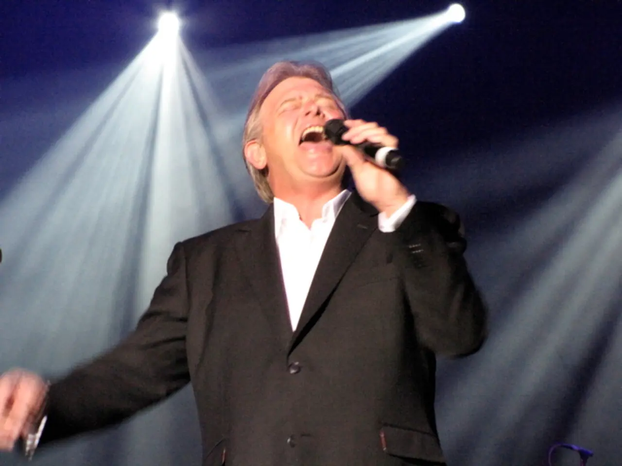 This picture is mainly highlighted with a man holding a mike in his hand and singing. These are...