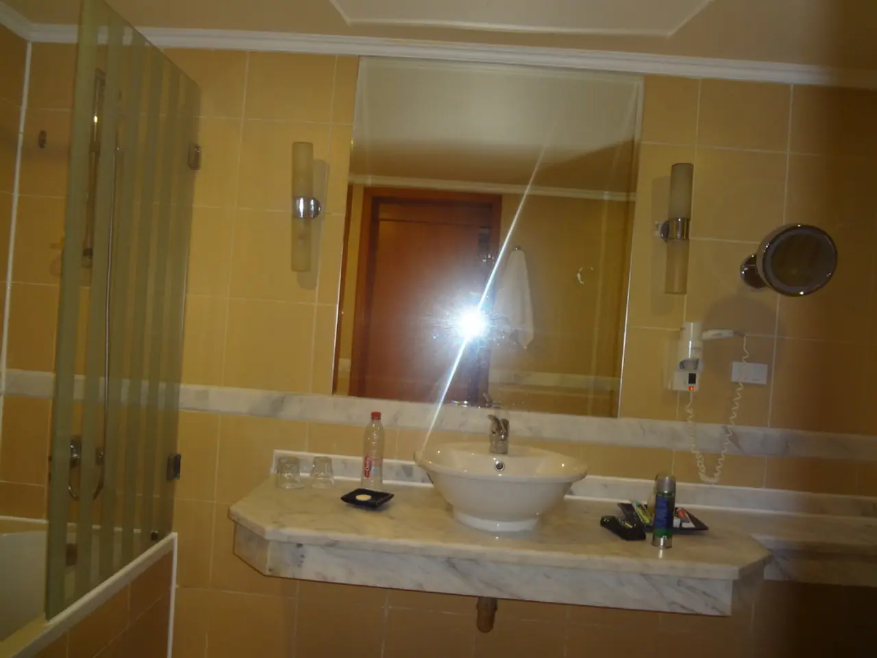 In this picture there is a wash basin, water glasses, hand wash and mirror