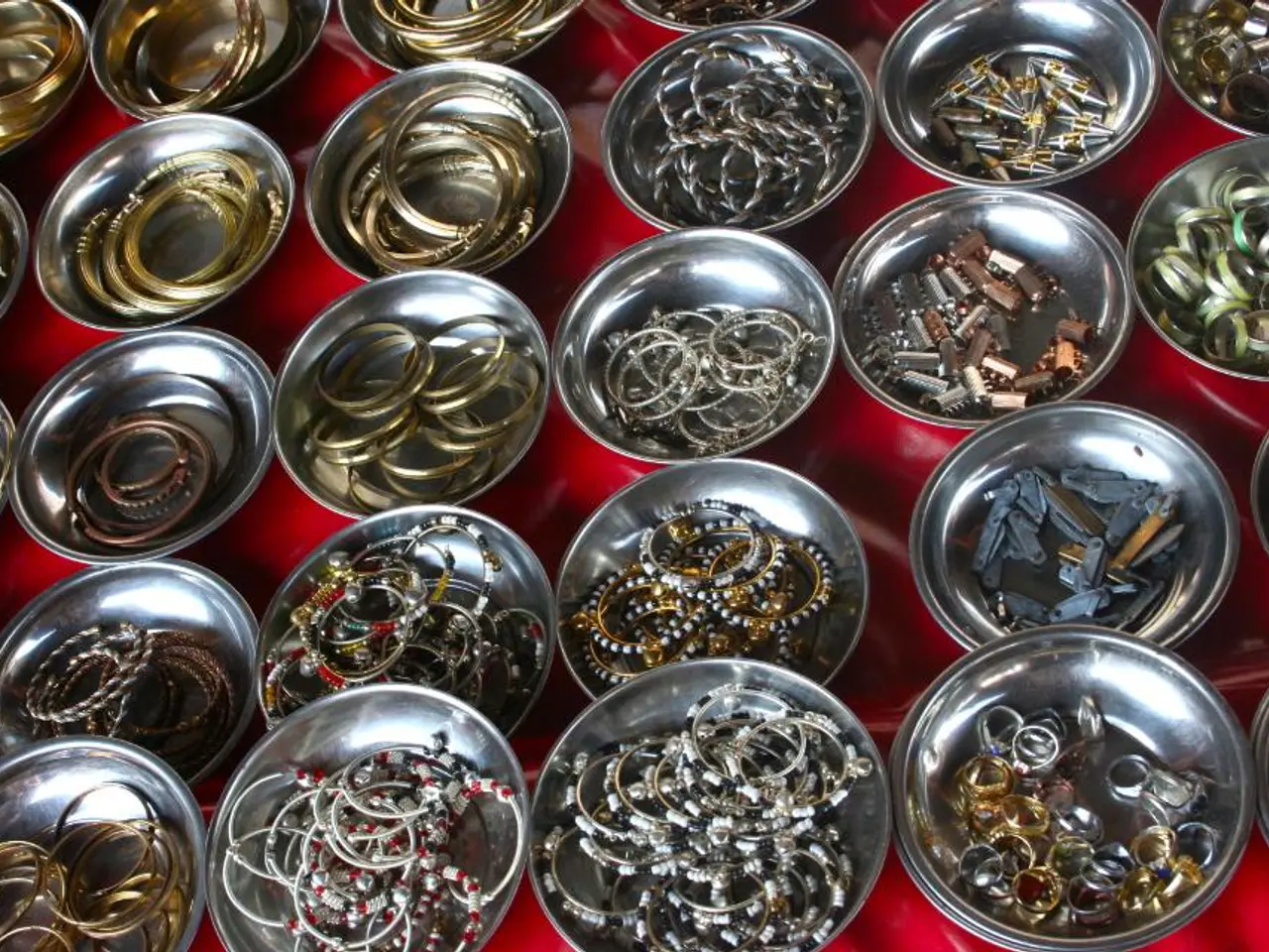 In this image there is a table with a table cloth and many plates with bangles, chains, rings,...