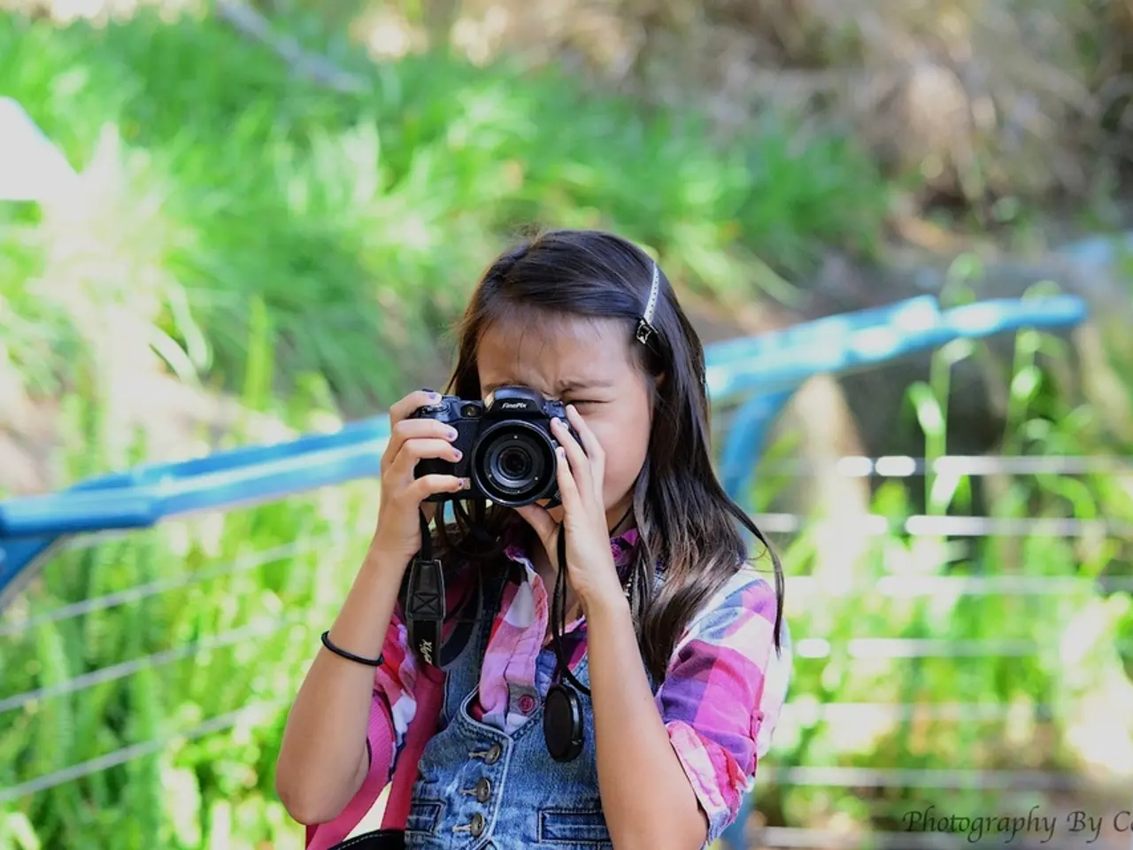 In this image in the center there is one girl who is holding a camera and clicking pictures, on the...