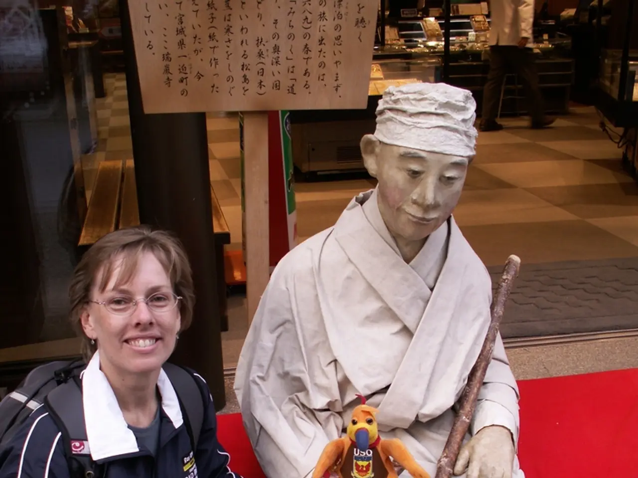 In this image we can see a person holding a bottle beside the statue and there is a toy and a stick...