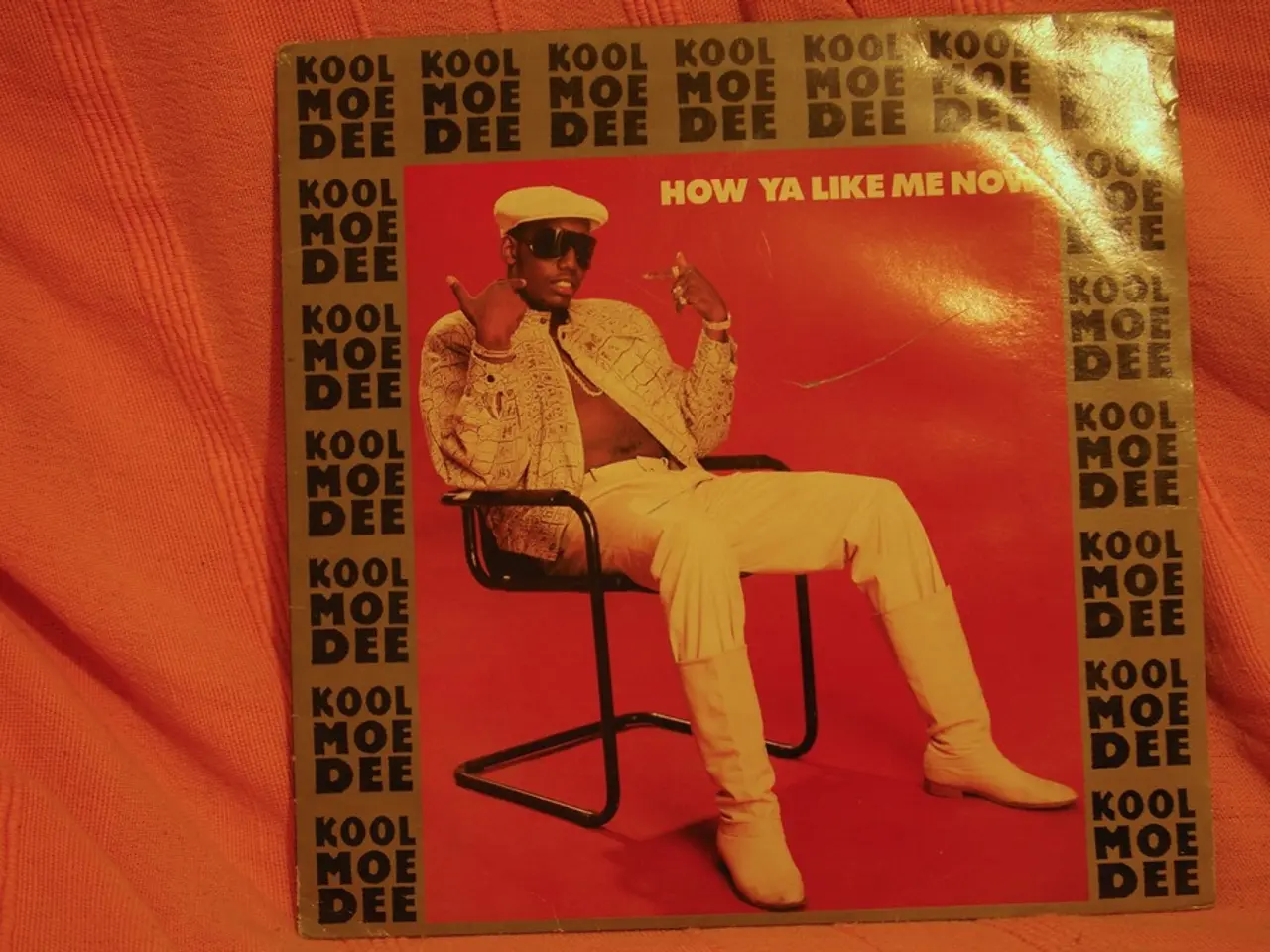 This is a picture of a poster. In the poster there is a man sitting in chair, he is wearing a cap...