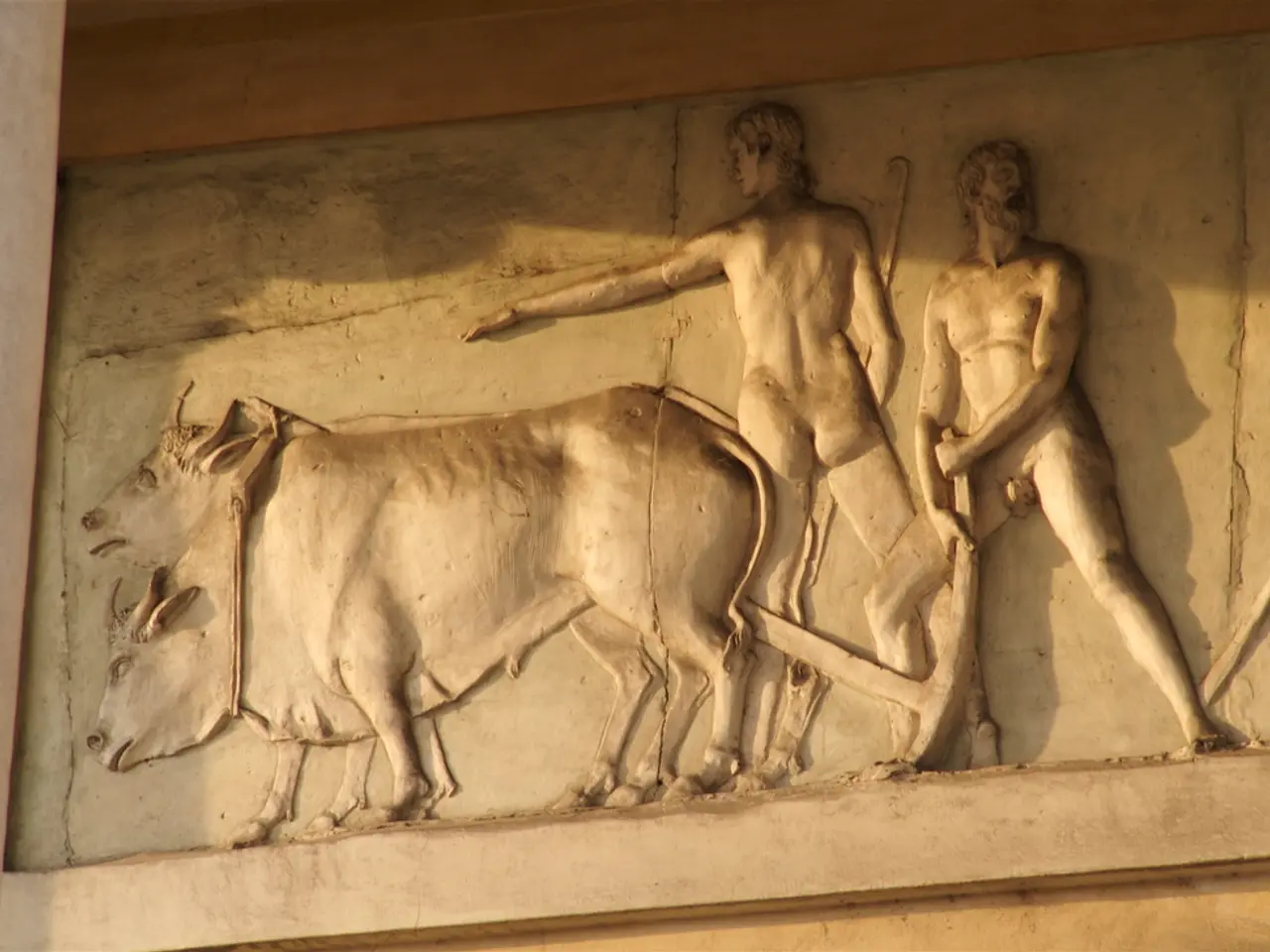 In this image we can see carvings on a stone on the wall where as we can see two persons are...