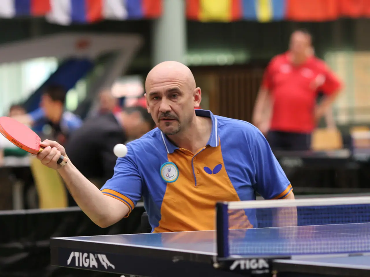 In this image, There is a table which is in black color, In the middle there is a man standing and...