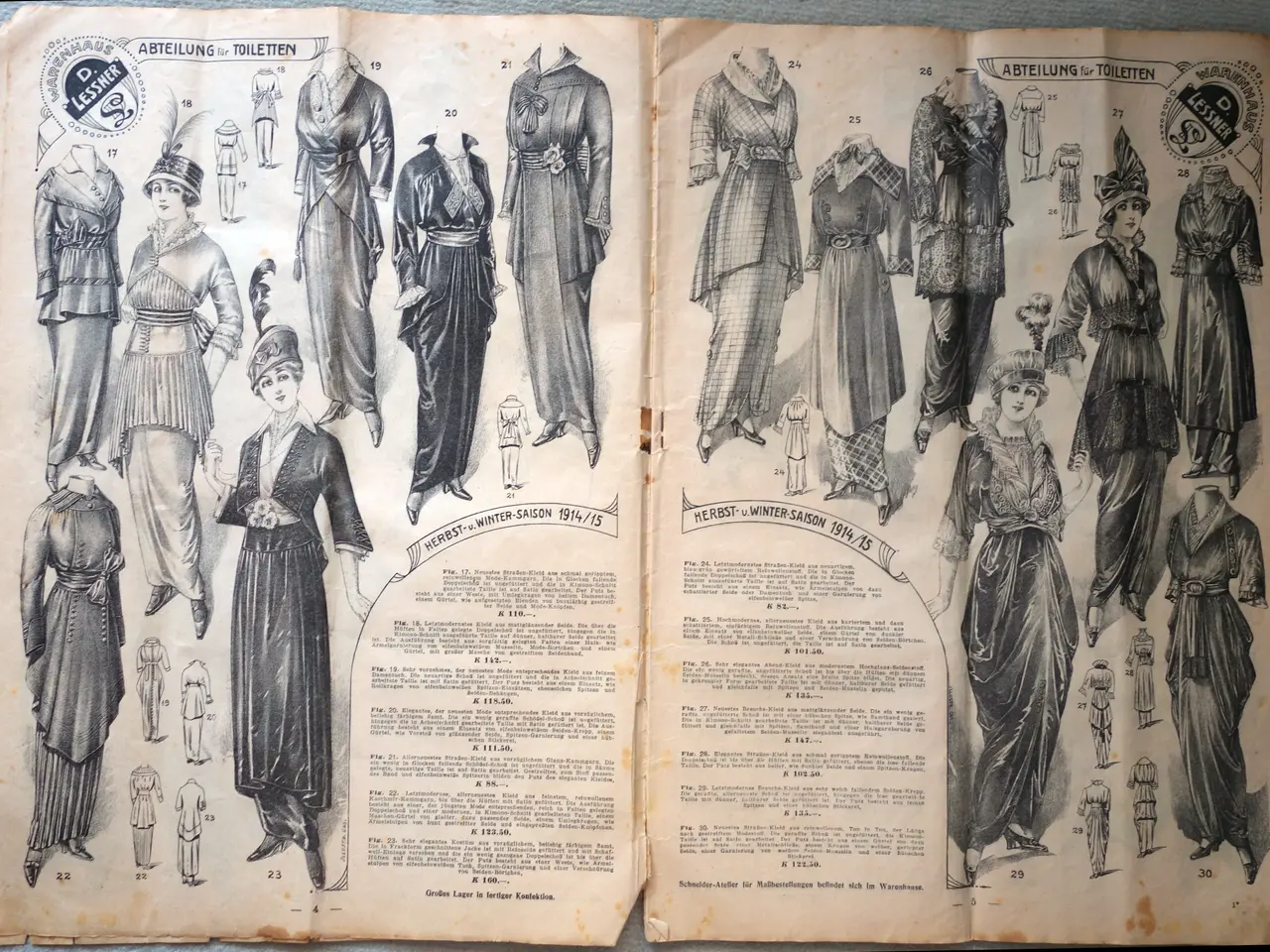 The image shows an open book with pictures of women's dresses on it, placed on a surface. The book...