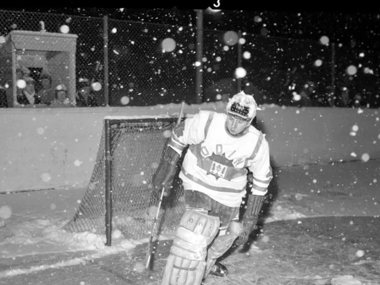 The image shows a black and white photo of a hockey player on the ice, wearing a helmet, gloves,...