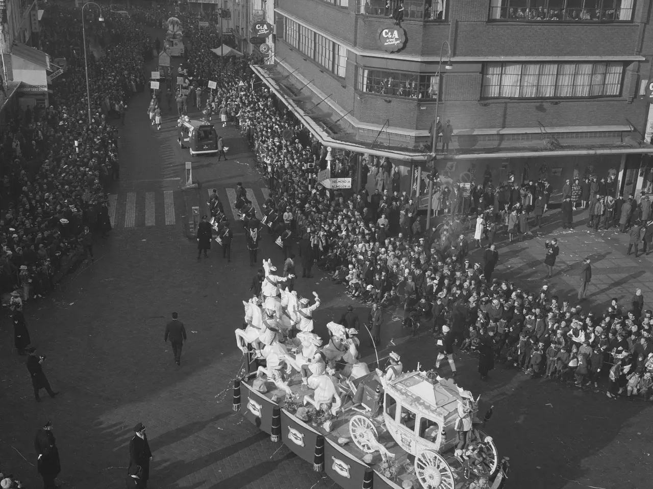The image shows a large crowd of people gathered around a float in a parade. The float is decorated...