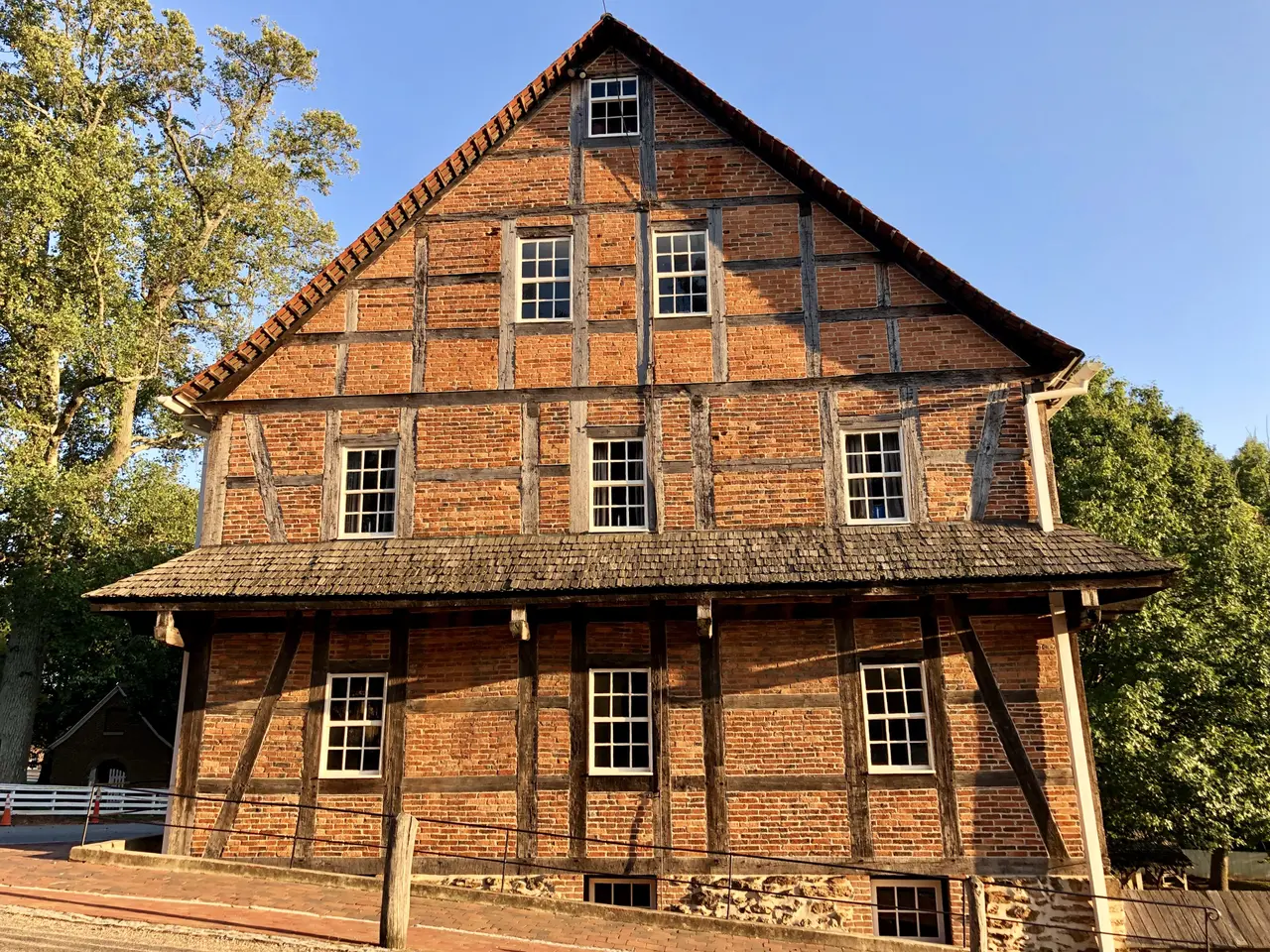 The image shows an old brick building with a clock tower in the middle of it, surrounded by a fence...