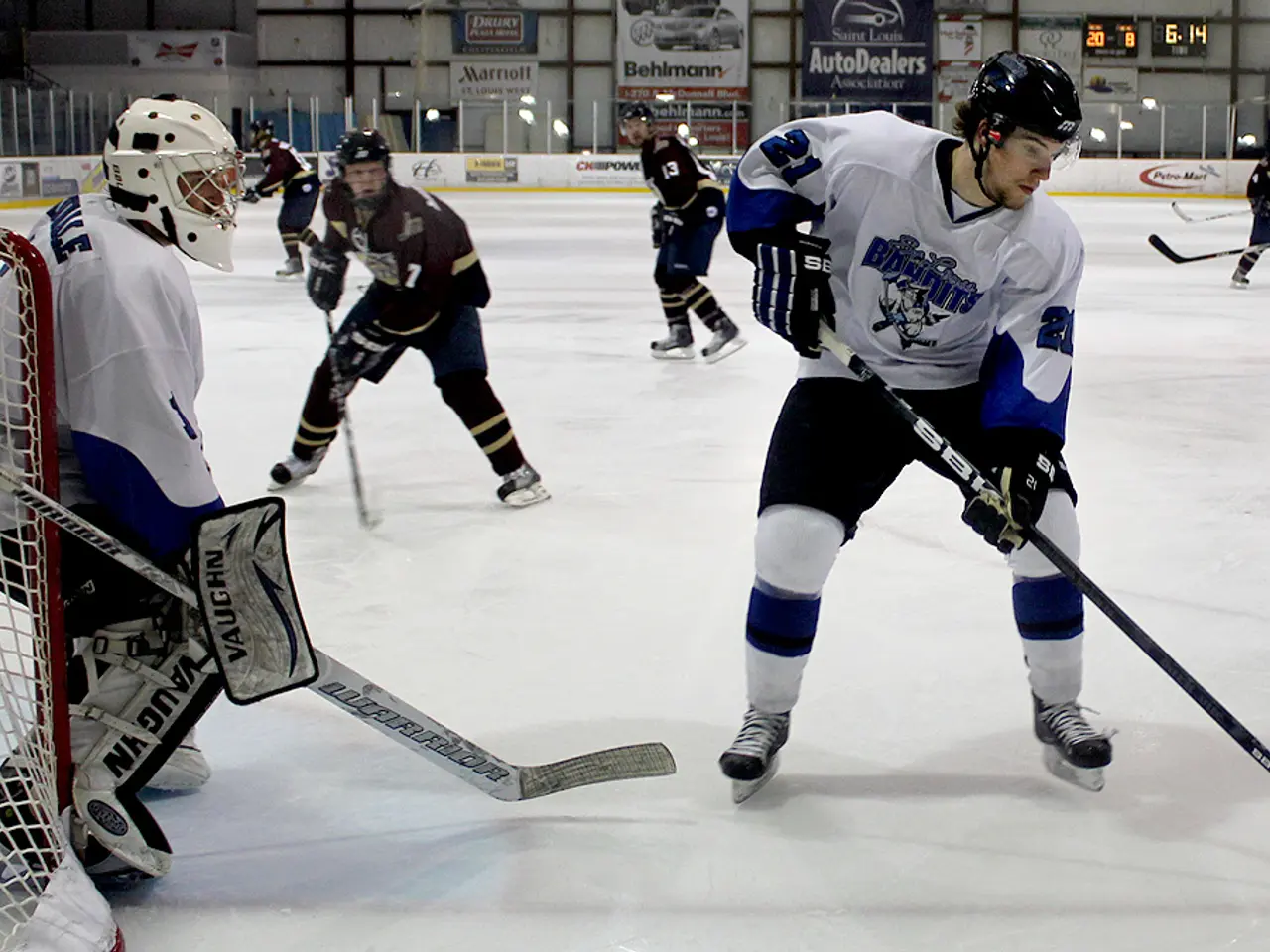The image shows a group of young men playing a game of ice hockey on an ice rink. They are all...
