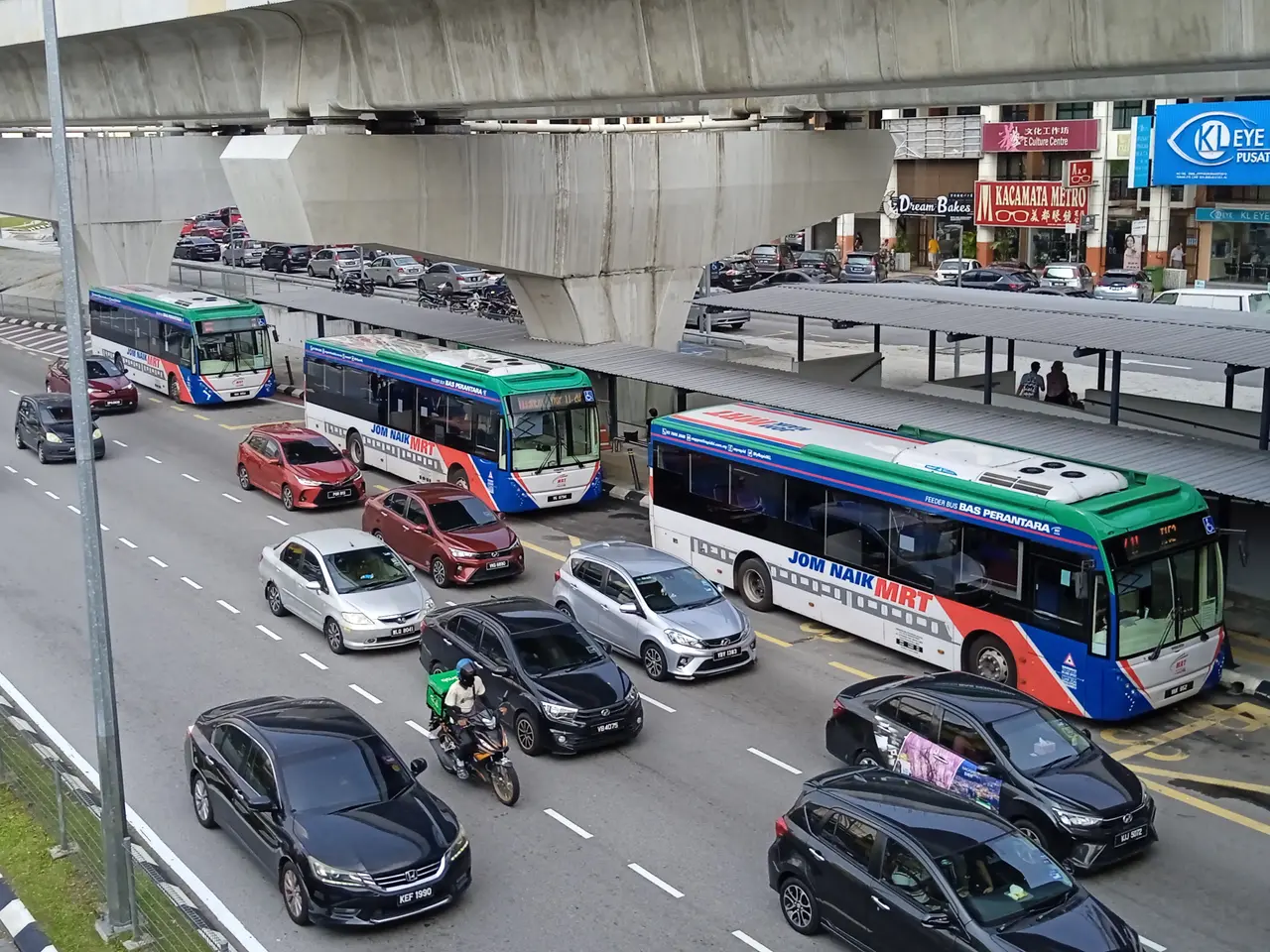 The image shows a busy street filled with lots of cars and buses, as well as a person riding a...