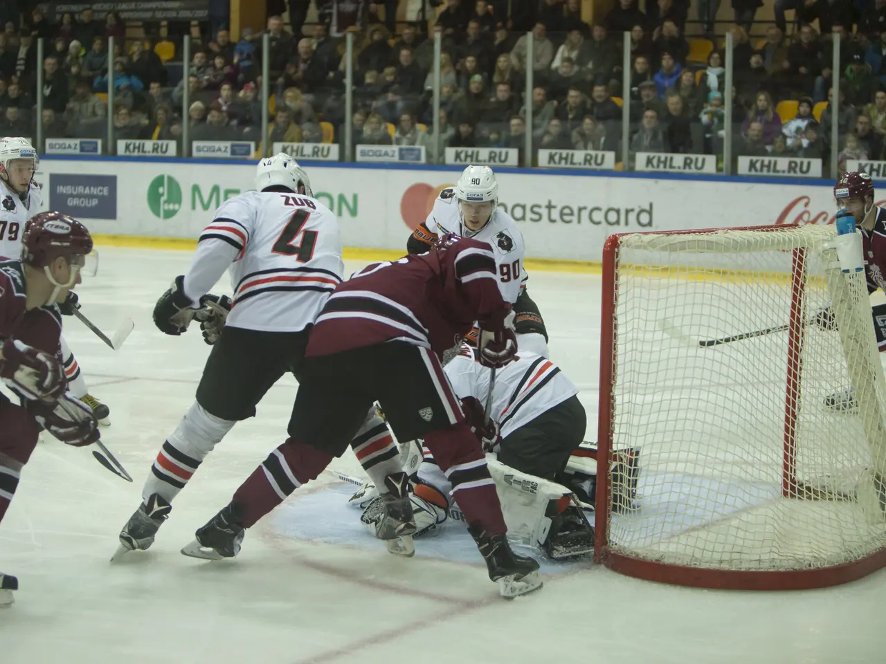 The image shows a group of people playing a game of hockey on an ice rink. They are wearing sports...