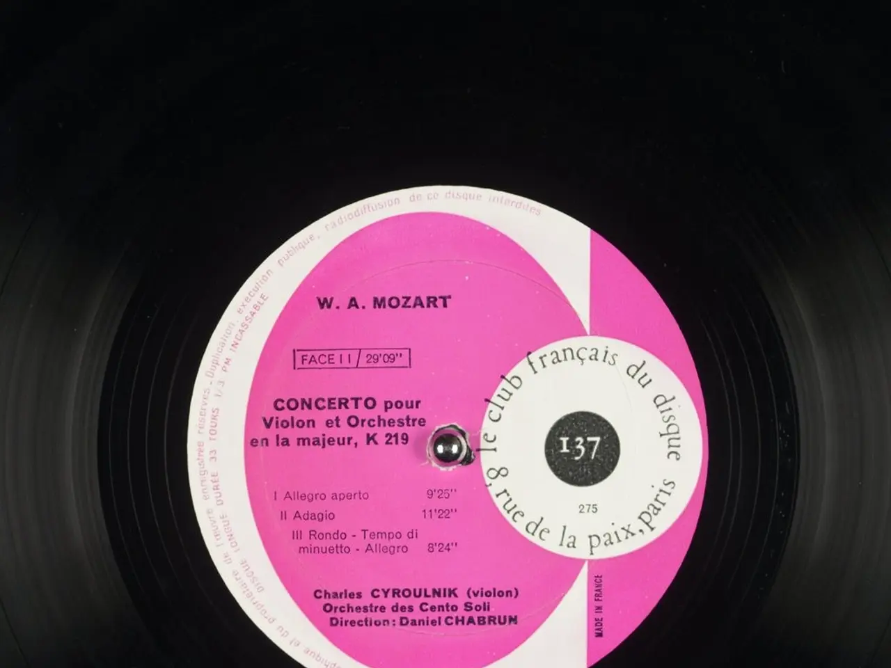 The image shows a black vinyl record with a pink label on it. The label reads "W.A. Mozart -...