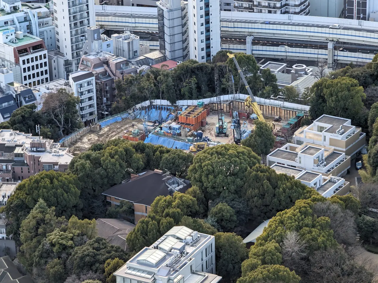 The image shows an aerial view of a construction site in the middle of a city, with buildings,...