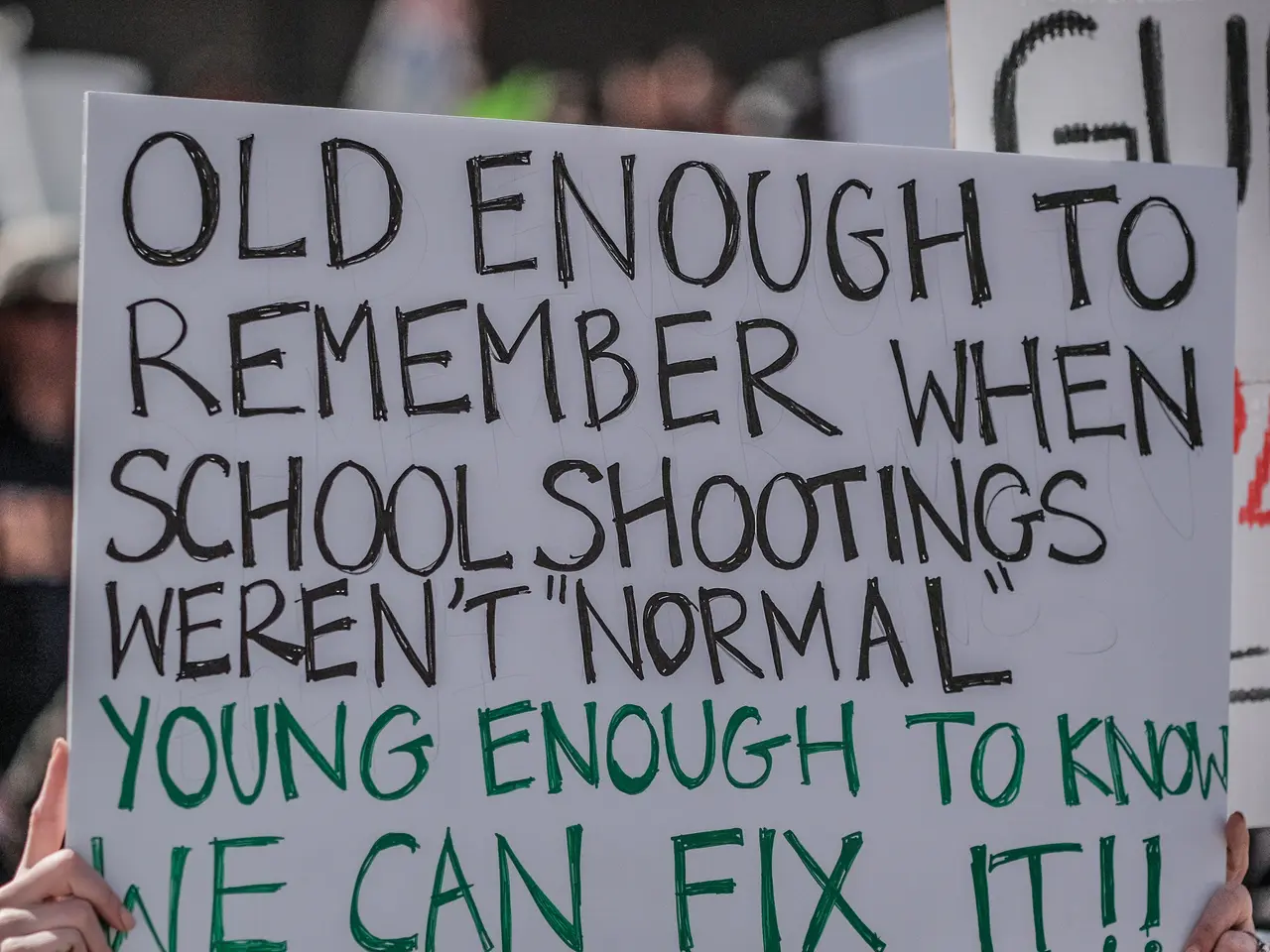 The image shows a woman wearing goggles and holding a sign that reads "Old enough to remember when...