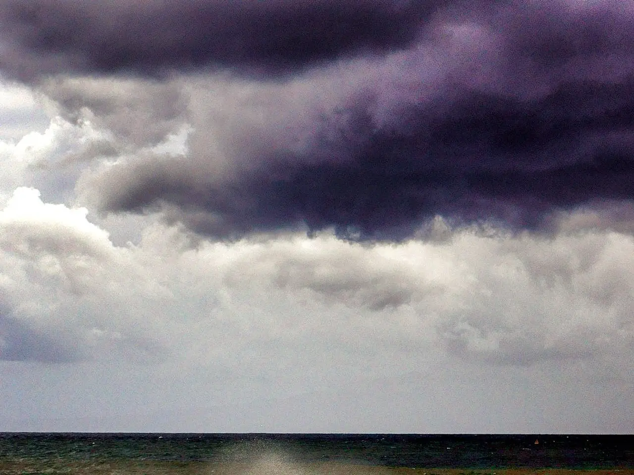 The image shows a stormy sky with dark clouds looming over the ocean, with waves crashing onto the...