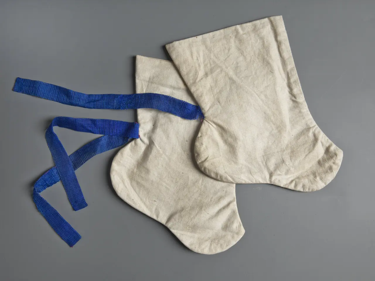 The image shows a pair of white socks with blue ribbons tied around them, creating a festive...
