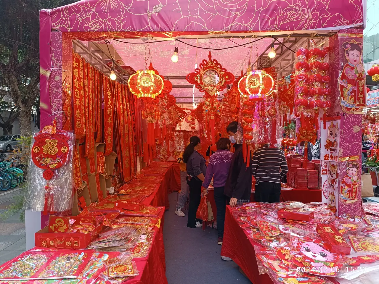 The image shows a bustling Chinese New Year market in Hong Kong, with people standing on the floor...