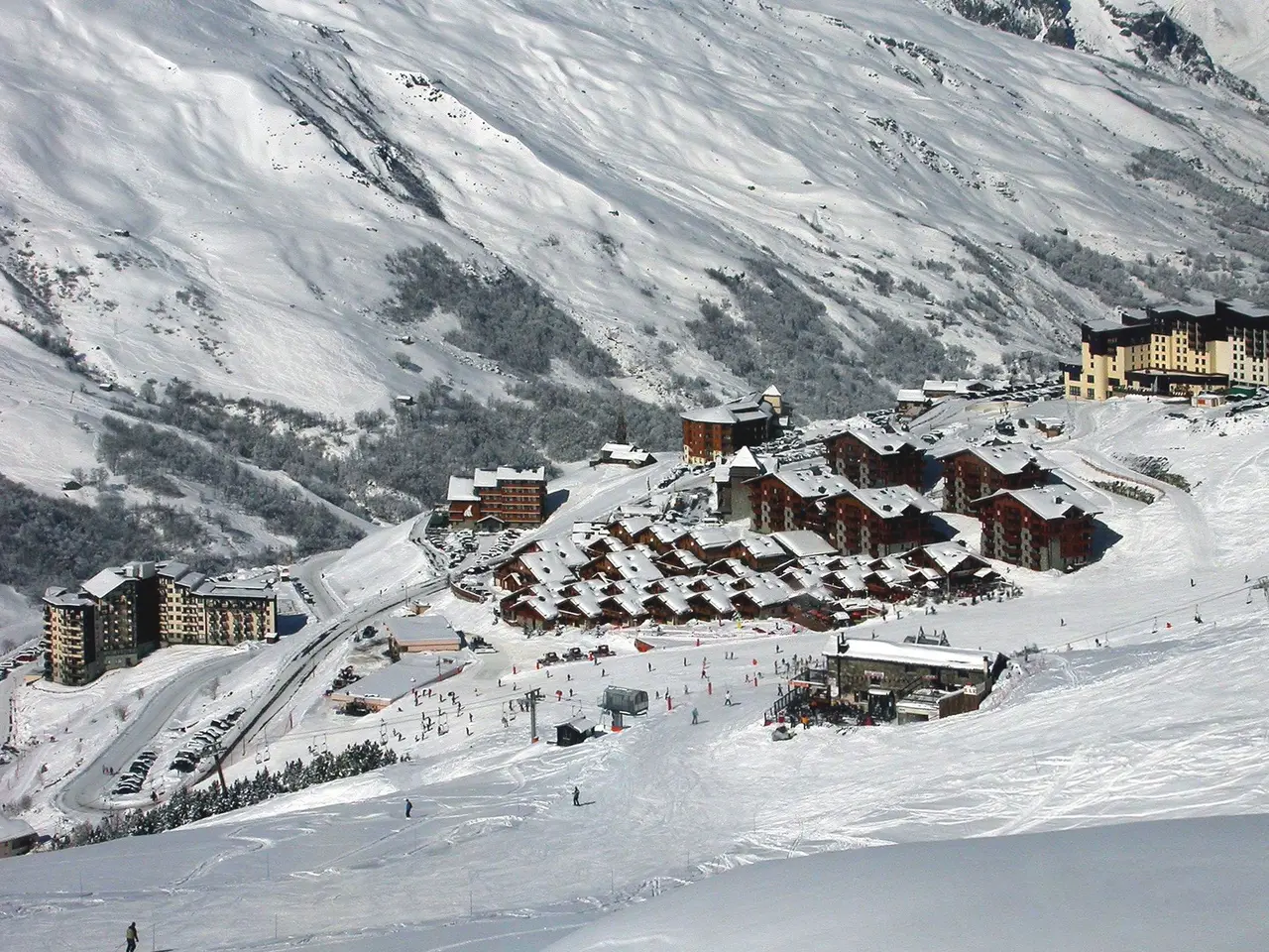 The image shows a picturesque view of a ski resort in the French Alps, with snow-covered mountains...