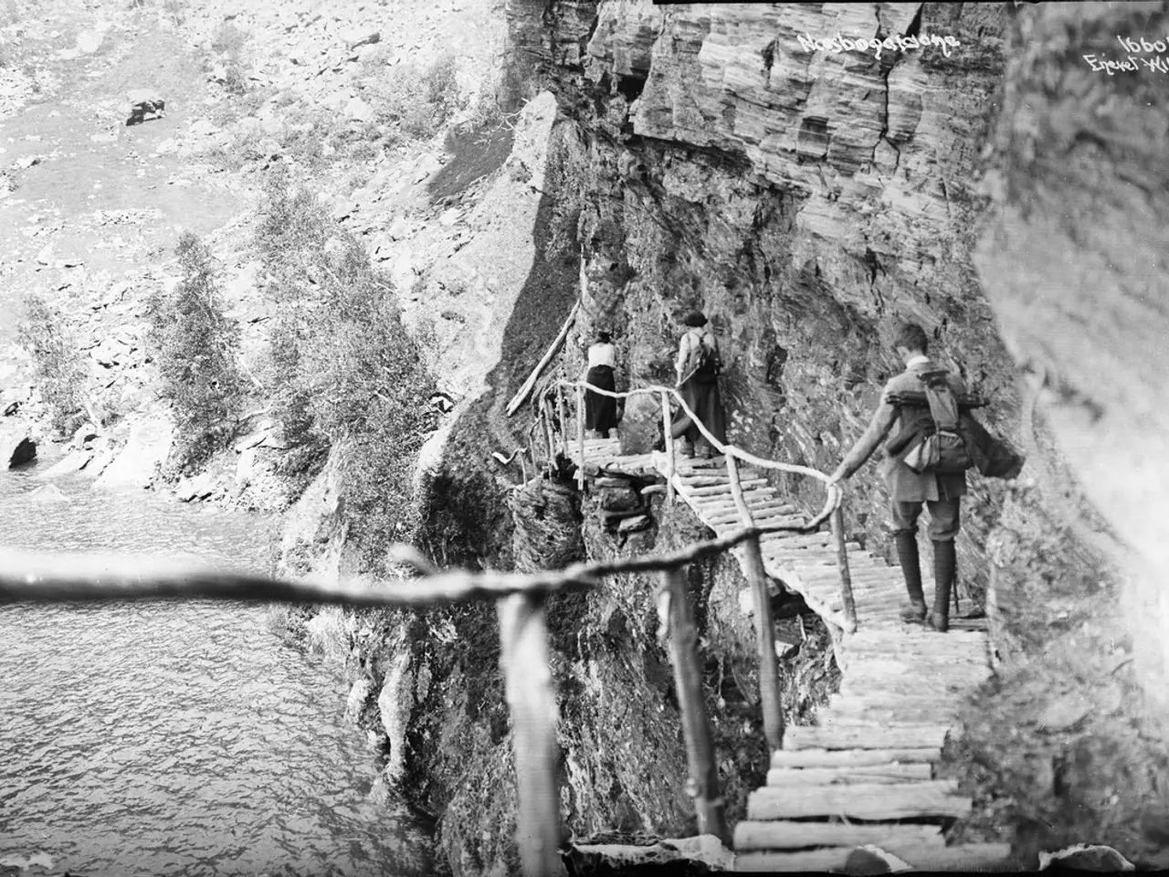 The image shows a group of people walking up a set of stairs, with a rope tied to a wooden pole on...