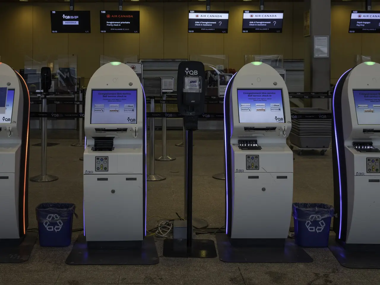 The image shows a row of automated teller machines sitting on top of a tiled floor, with dustbins,...
