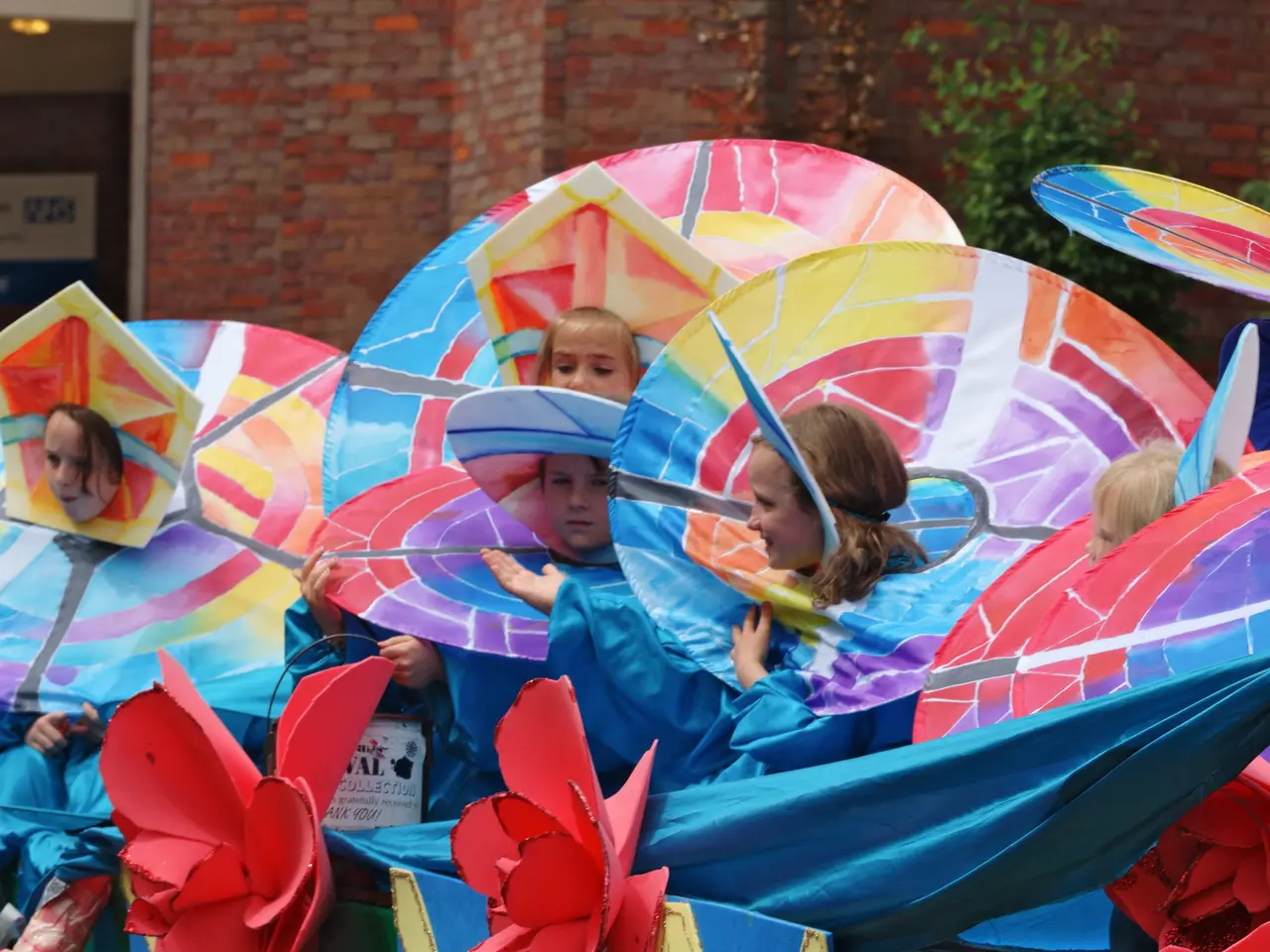 The image shows a group of children riding on top of a float in a parade, wearing colorful costumes...