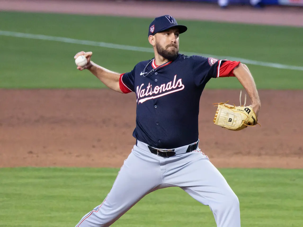 The image shows a baseball player wearing a cap and glove, pitching a ball on top of a grassy...