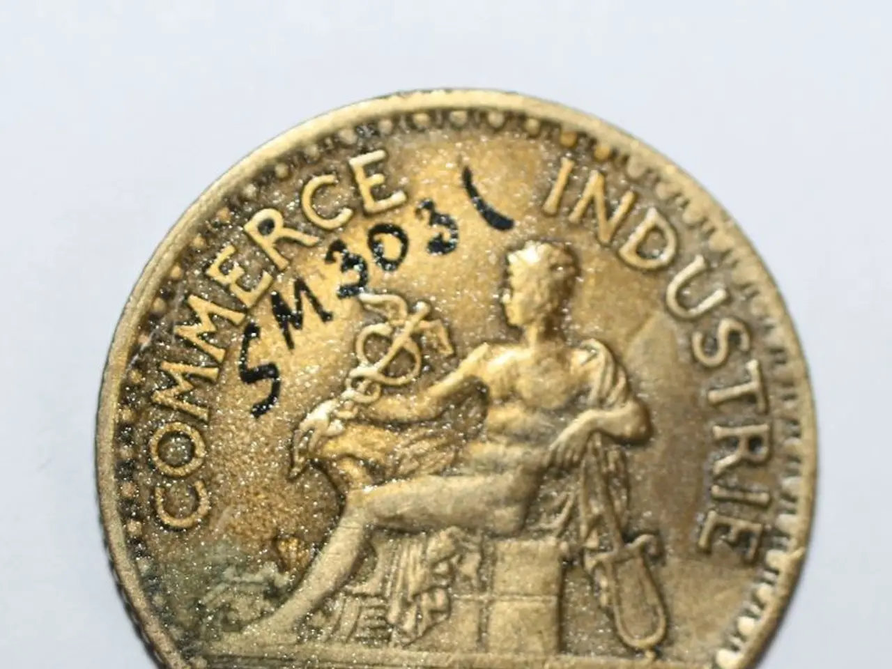 The image shows a gold coin with the words "Commerce Industrie" on it against a white background.