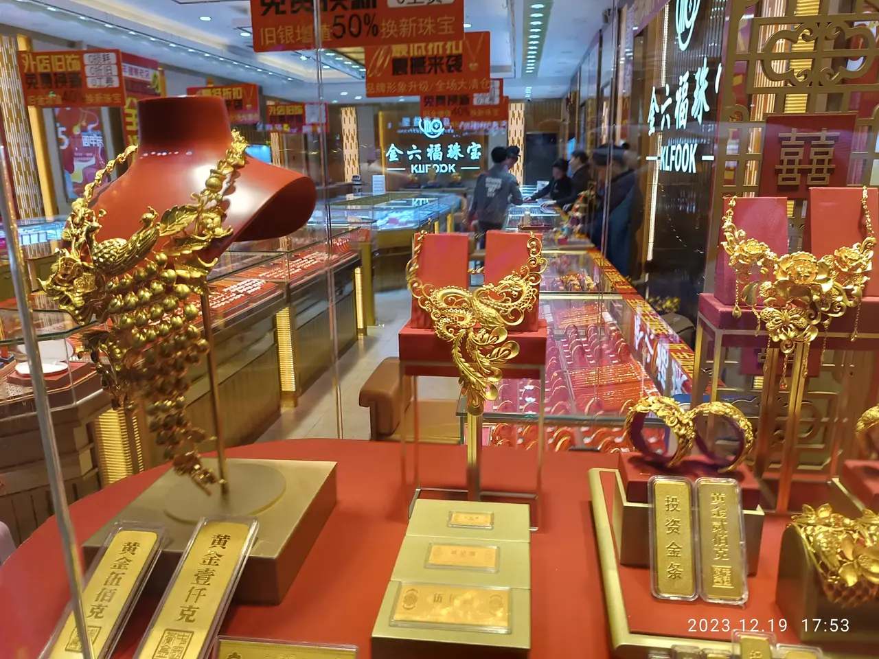 The image shows a store filled with lots of gold jewelry on display, including necklaces,...