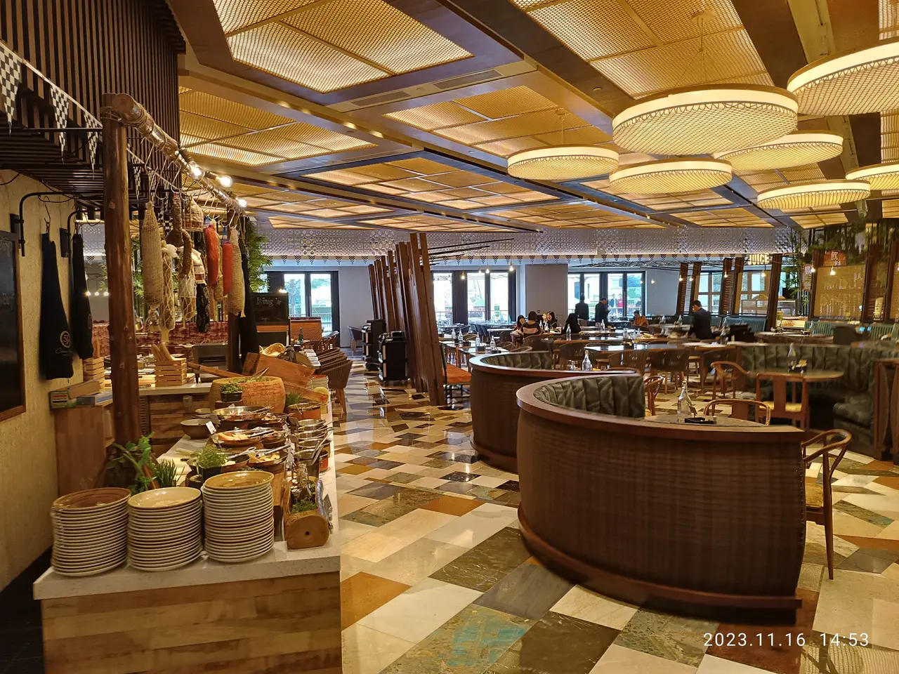 The image shows the interior of a restaurant with tables and chairs, plates, plants, and other...