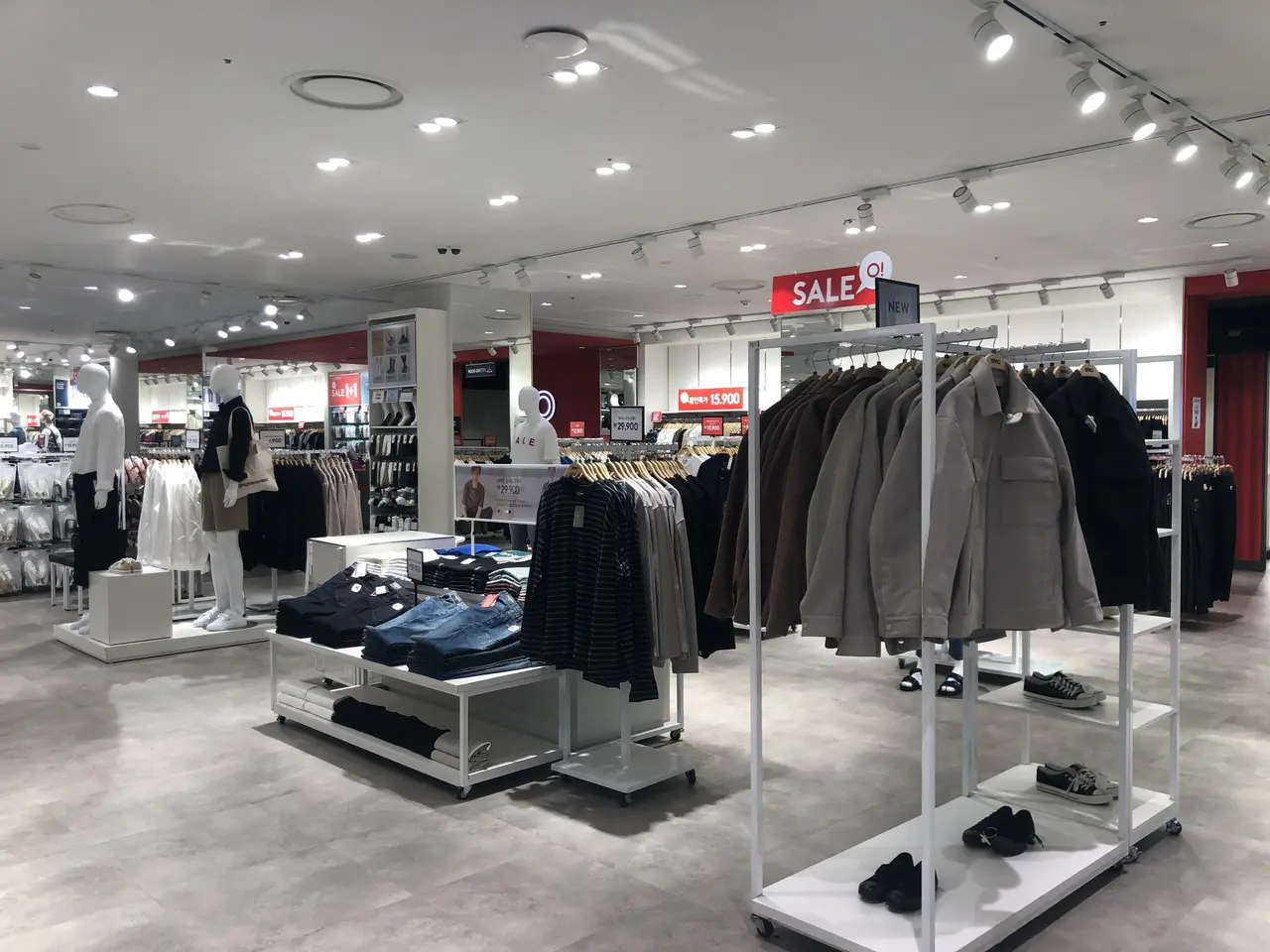 The image shows the inside of a clothing store with mannequins, clothes on hangers, shoes on the...