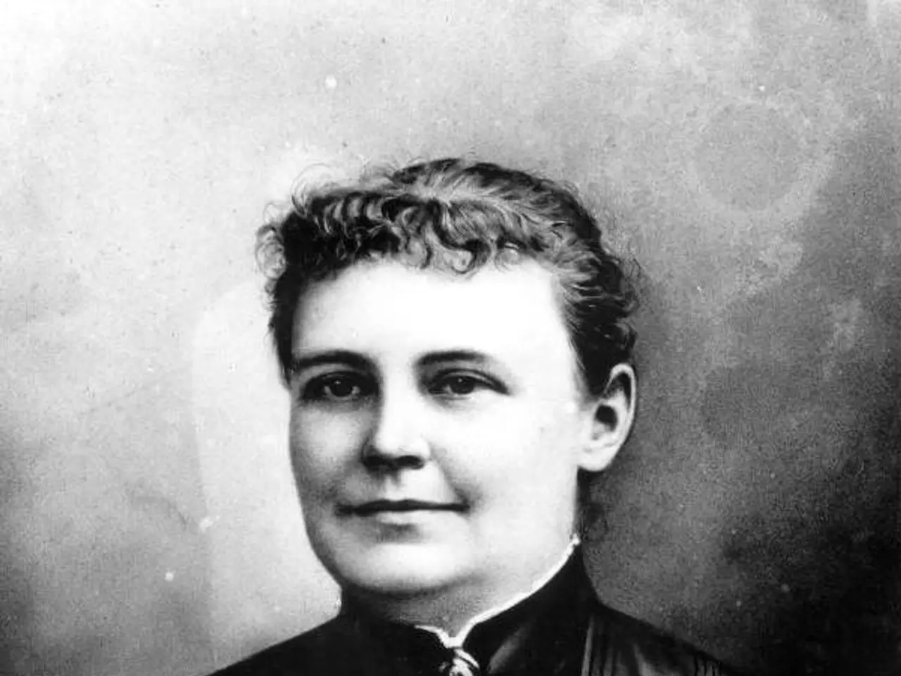 The image shows a black and white photo of a woman in a dress, believed to be the first woman to be...